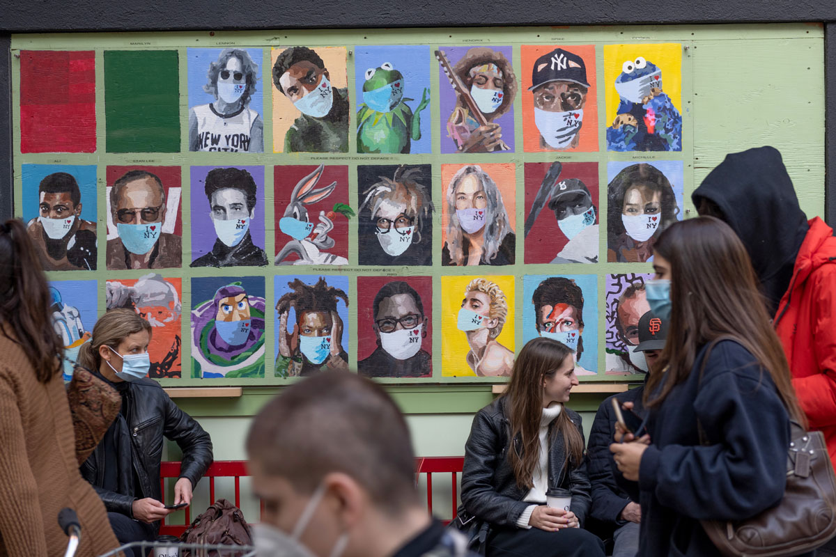 People walk past a mural of faces wearing masks at Olive's in SoHo on October 18 in New York City.