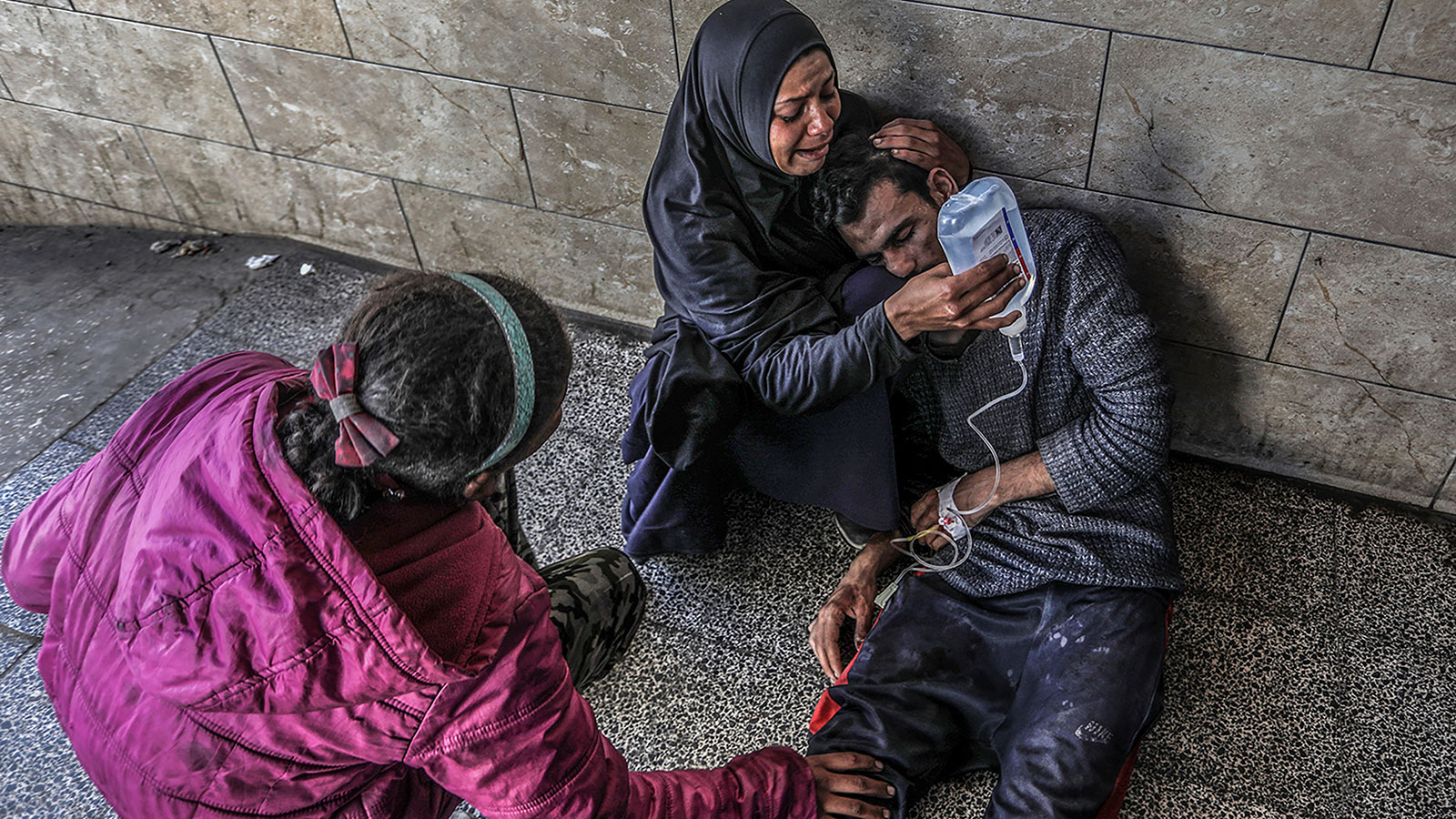 A Palestinian woman holds a glucose solution for her relative, who was injured in an Israeli air strike near a warehouse of the United Nations Relief and Works Agency for Palestine Refugees, at Al-Najjar Hospital in Rafah, Gaza. 