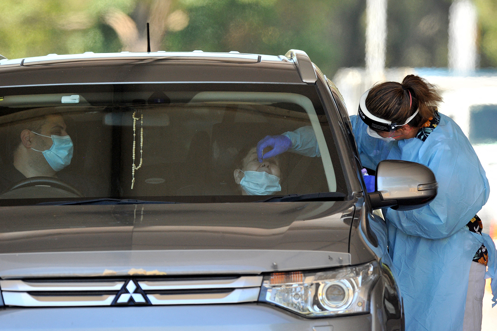 A medical worker takes a swab from a woman at a drive-through Covid-19 test center in western Sydney on December 21.