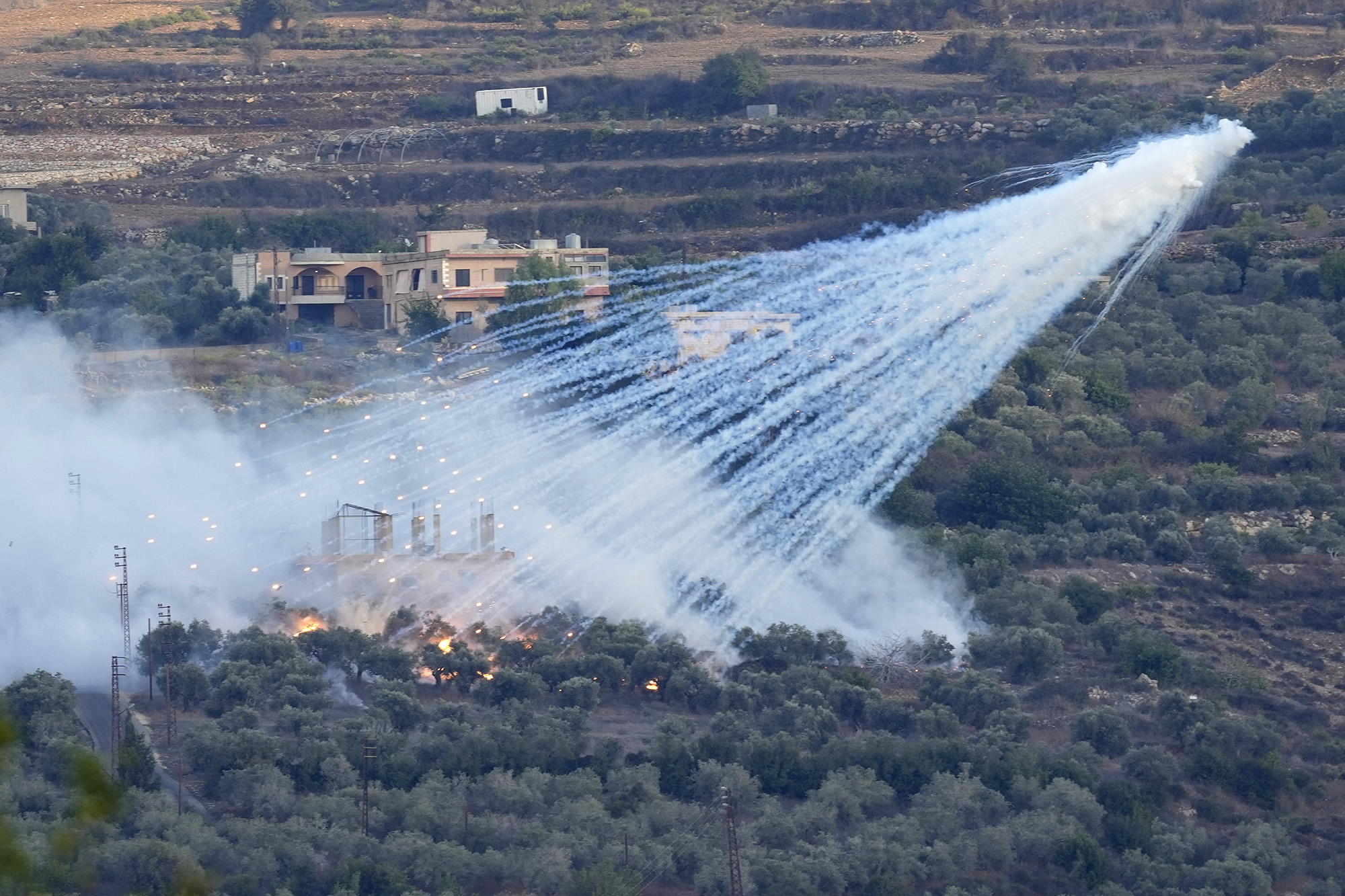 A shell that appears to be white phosphorus explodes over a house in al-Bustan, south Lebanon, on October 15.