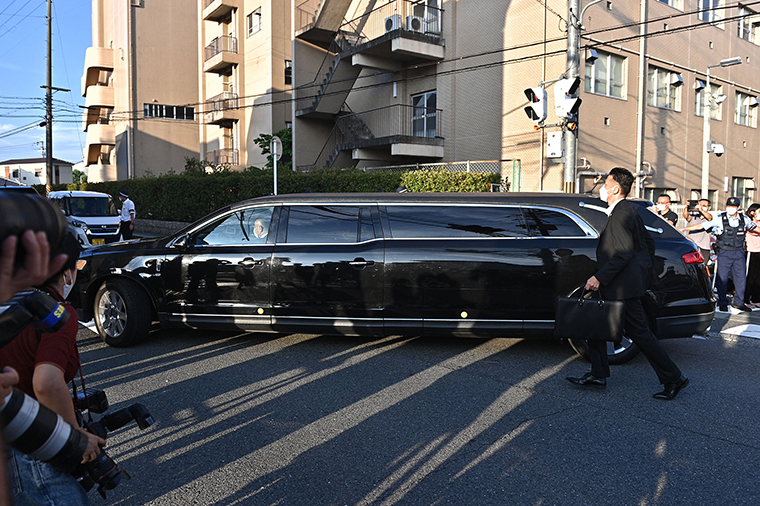 The car believed to carry the body of Japan's late former prime minister Shinzo Abe passes by policemen and media outside the Nara Medical University Hospital in Kashihara, Nara Prefecture early on July 9.