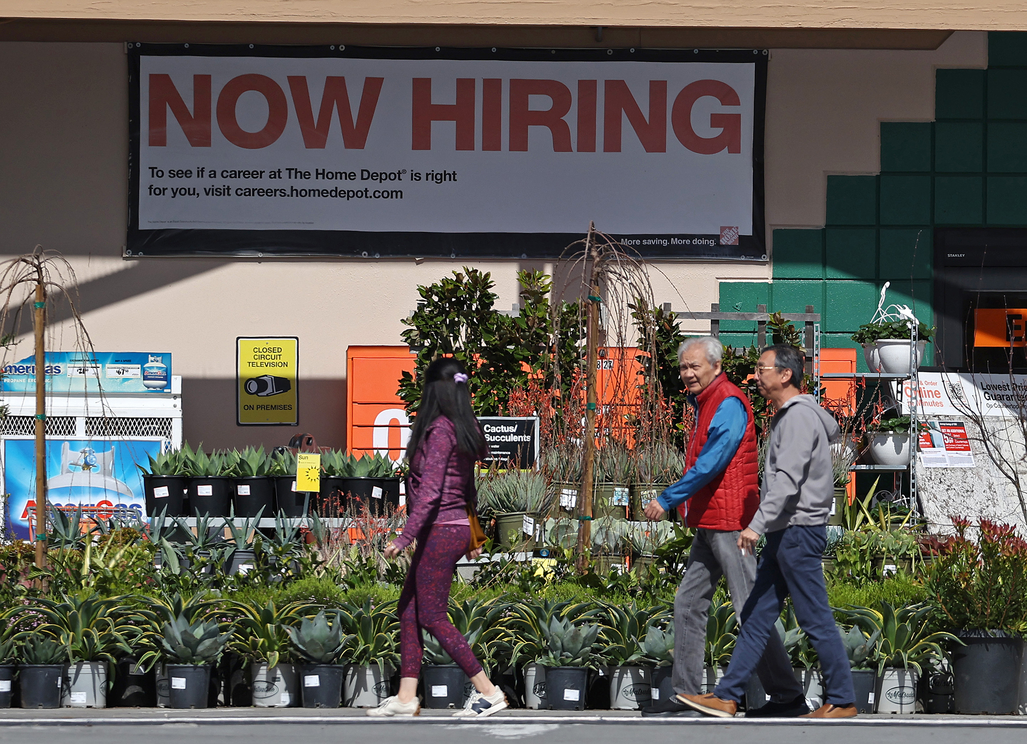 People walk by a posted now hiring sign on March 08, 2024 in San Rafael, California.