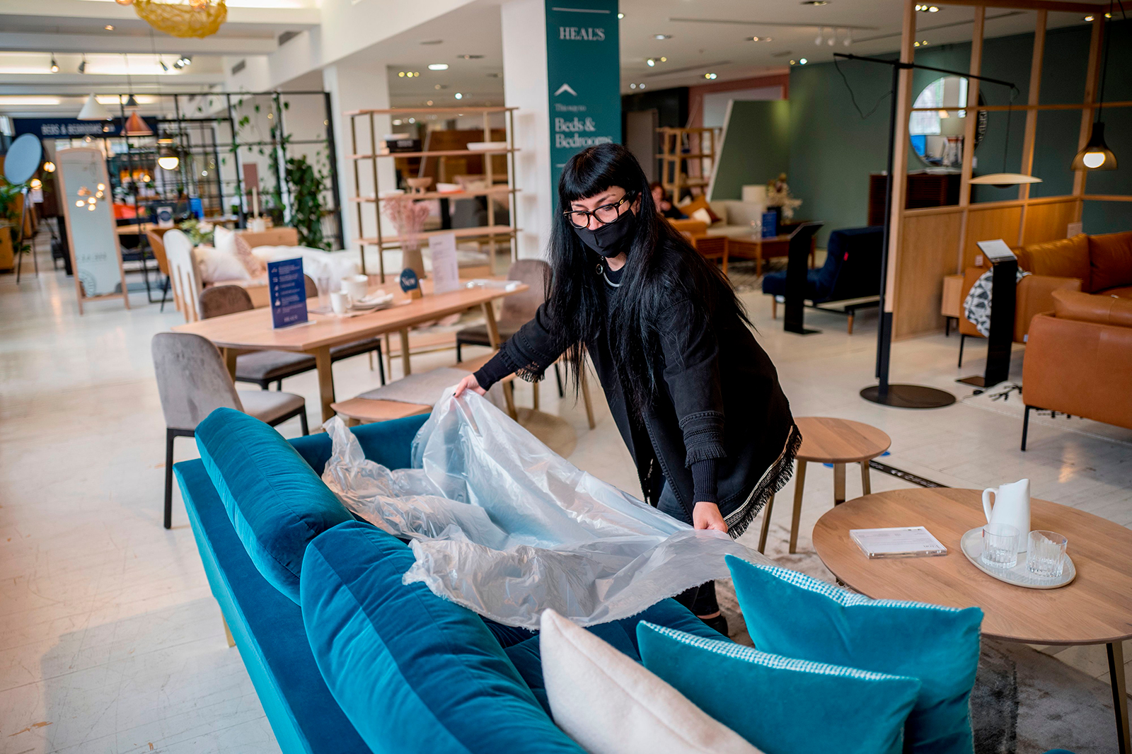 A woman demonstrates the use of plastic film for customers to test sofas, at the re-opened Heal's flagship store in central London on June 8.