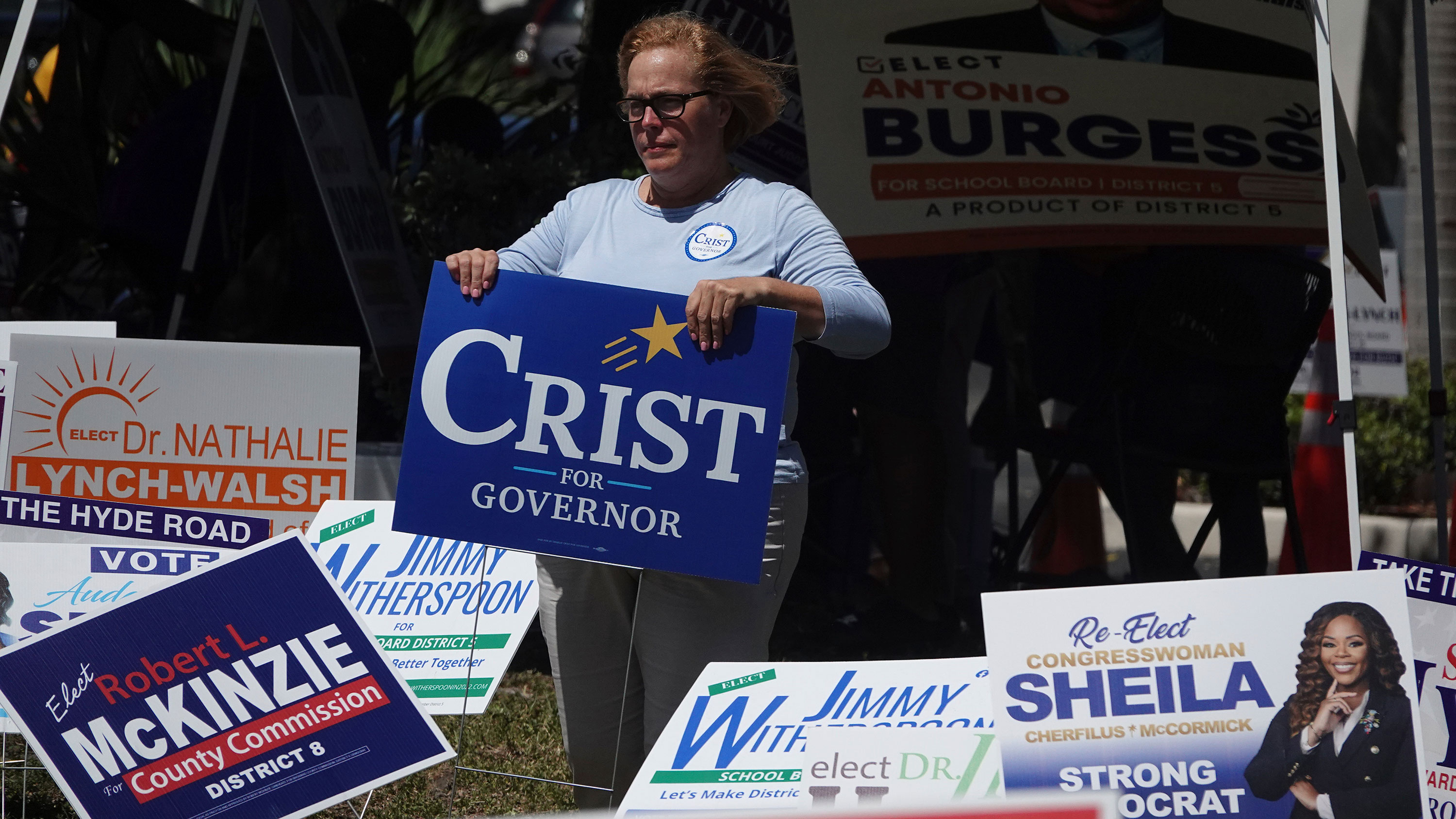 A campaign worker places a sign at outside of a polling place in Fort Lauderdale, Florida, on August 21.
