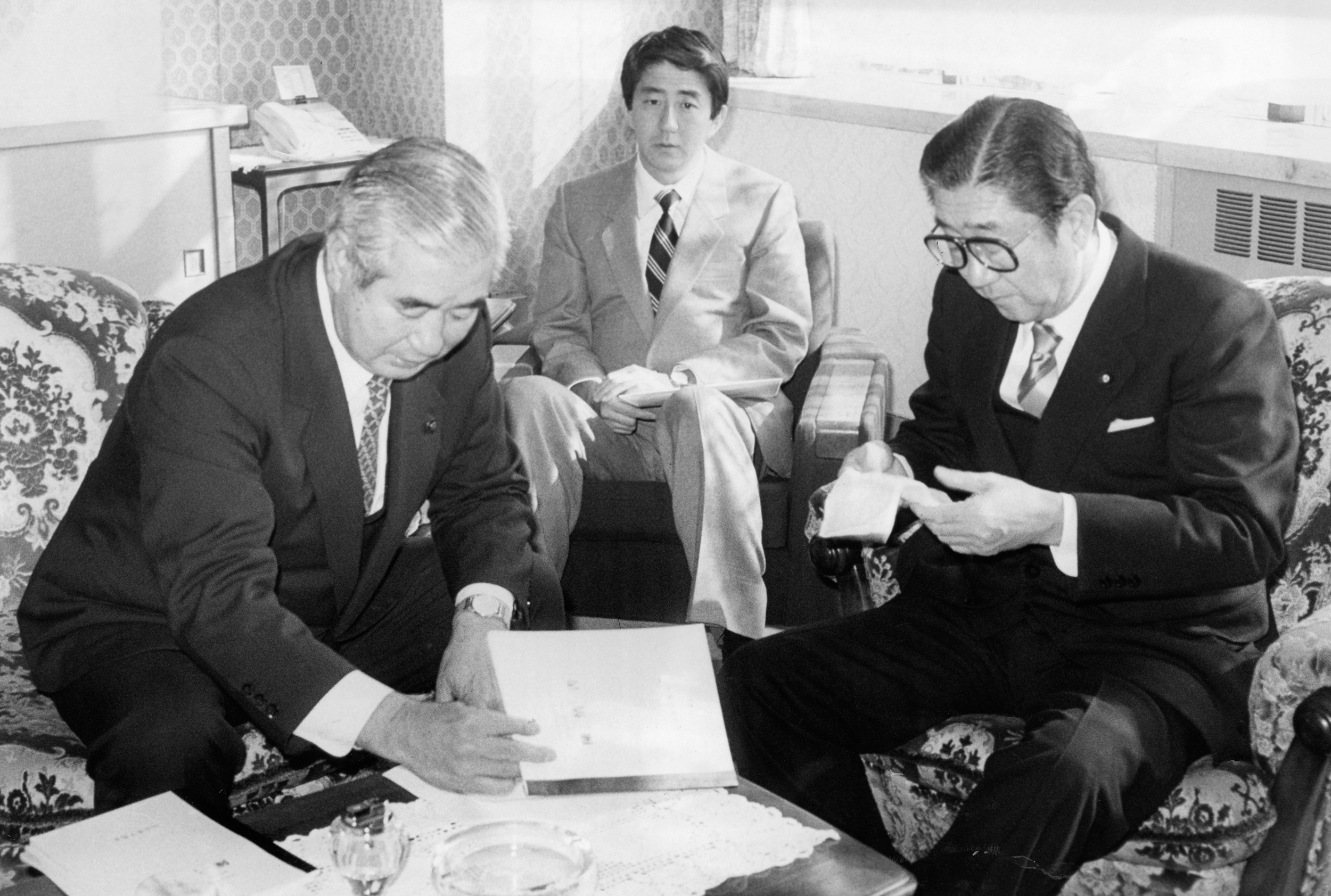 Liberal Democratic Party secretary general Shintaro Abe, right, and his son and secretary Shinzo Abe, center, visit their hometown Shimonoseki mayor Yoshitsugu Izumida, left, at Shimonoseki City Hall on January 16, 1988, in Shimonoseki, Yamaguchi, Japan. 