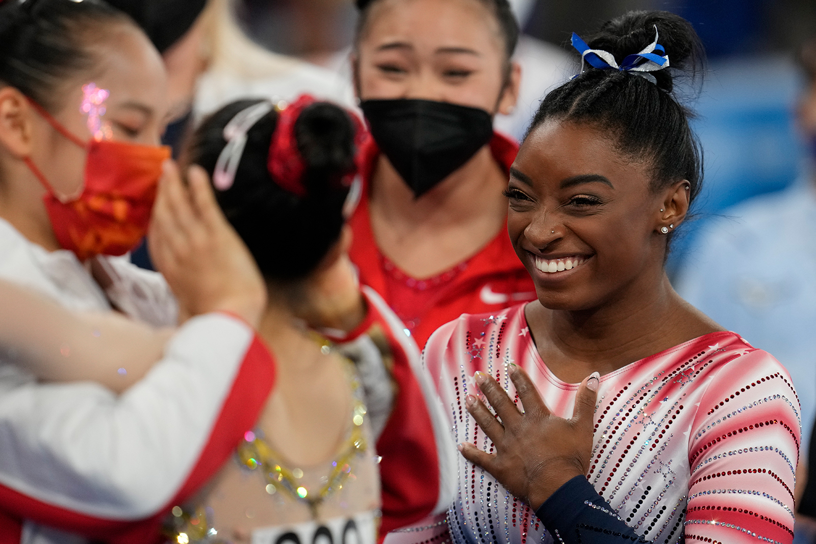 American gymnast Simone Biles smiles as China's Tang Xijing embraces teammate Guan Chenchen at the balance beam final on August 3.