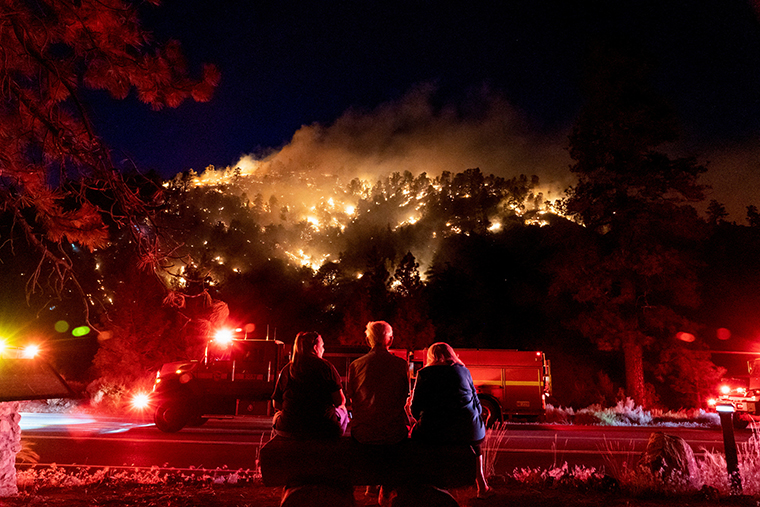 Residents watch part of the Sheep Fire wildfire burn through a forest on a hillside near their homes in Wrightwood, California, on June 11.