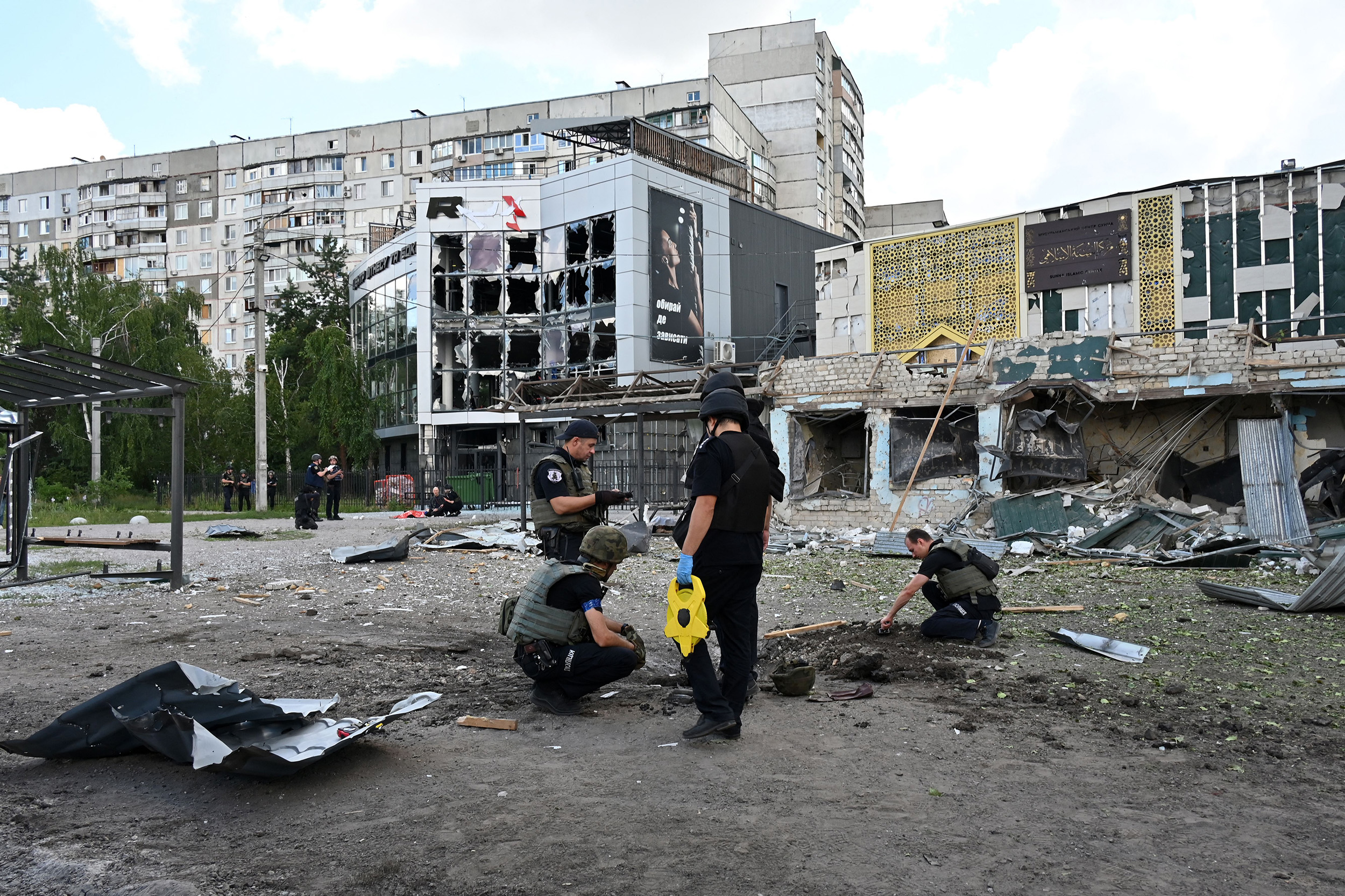 Police experts examine a crater left by a Russian missile strike at a bus stop in Saltivskyi, a northern district of of Kharkiv on July 20.