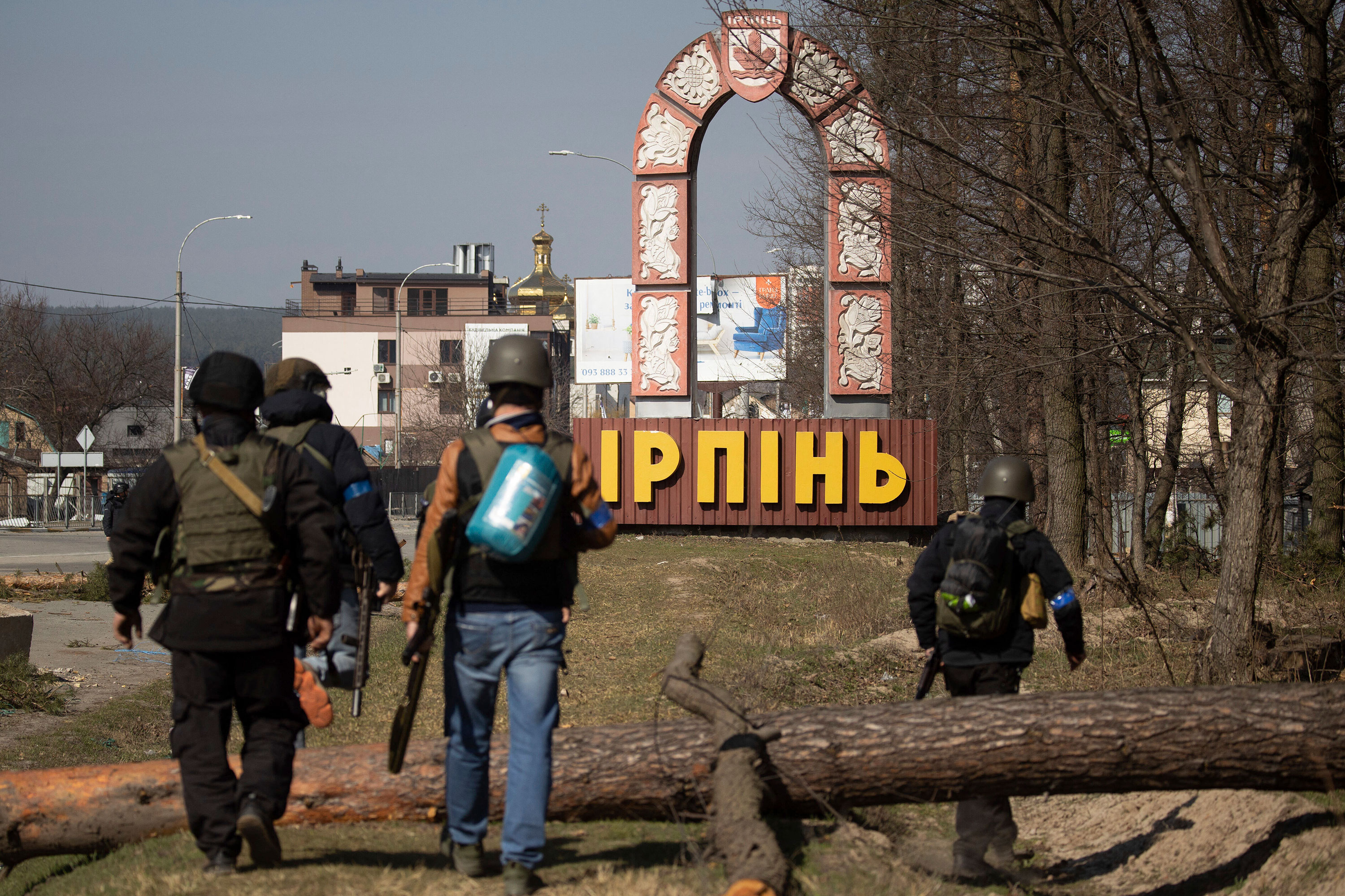 Ukrainian soldiers walk toward a sign at the entrance to the city of Irpin on March 29.