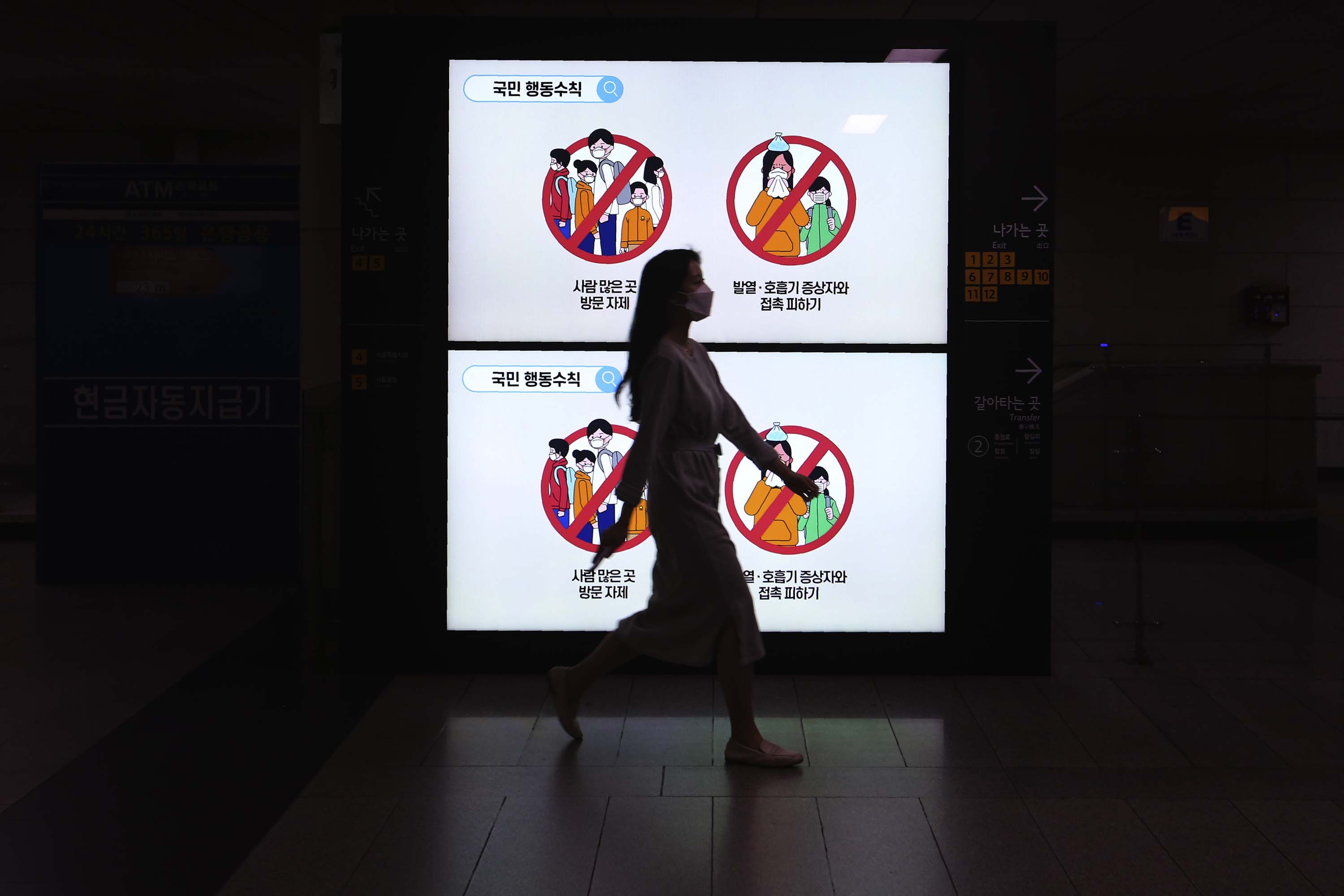 A person wearing a face mask passes by screens showing civil behavior guidelines for protection against the spread of coronavirus at a subway station in Seoul, South Korea, on Thursday, May 28. 