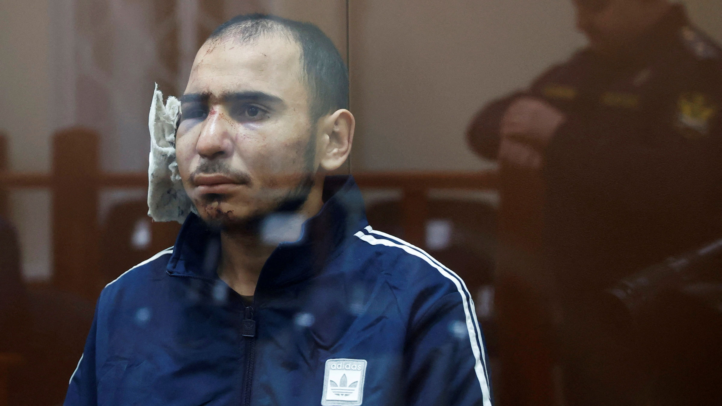 Saidakrami Rachabalizoda, a suspect in the deadly terrorist attack in Moscow, sits behind a glass wall of an enclosure during a court appearance on Sunday. His ear was heavily bandaged.