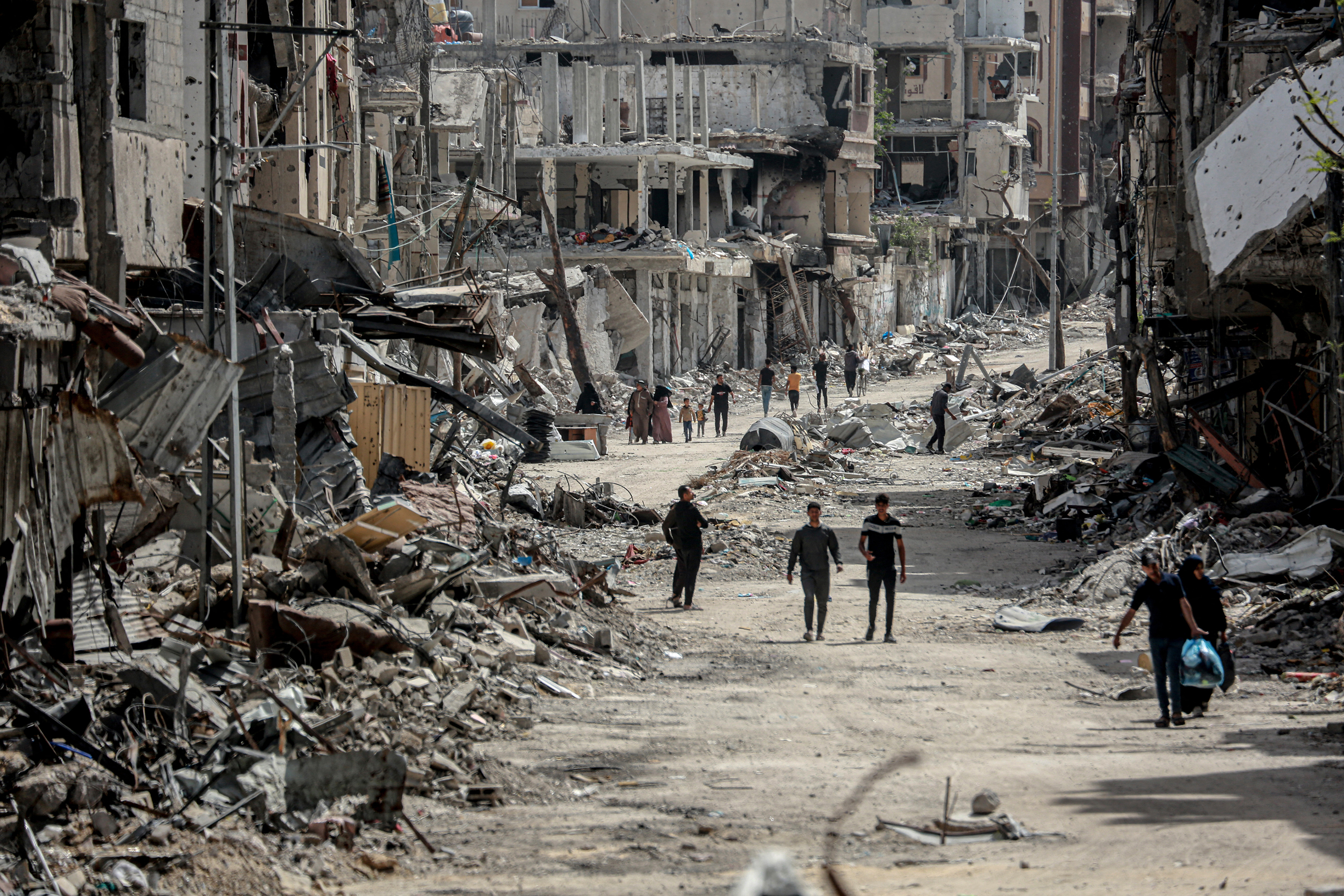 Palestinians walk on a road lined with destroyed buildings in Khan Younis, Gaza, on April 22.