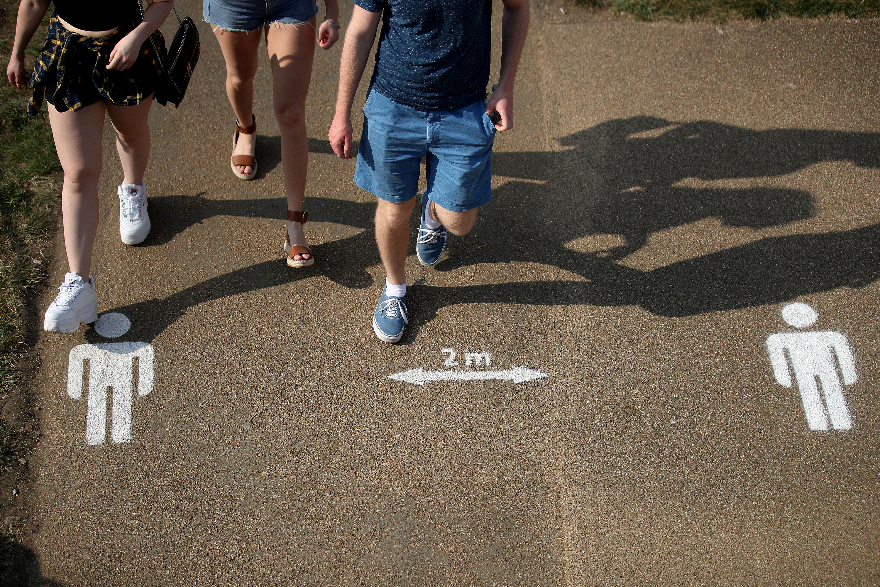 People walk past social distancing markers on the ground at Queen Elizabeth Olympic Park in London on April 11.