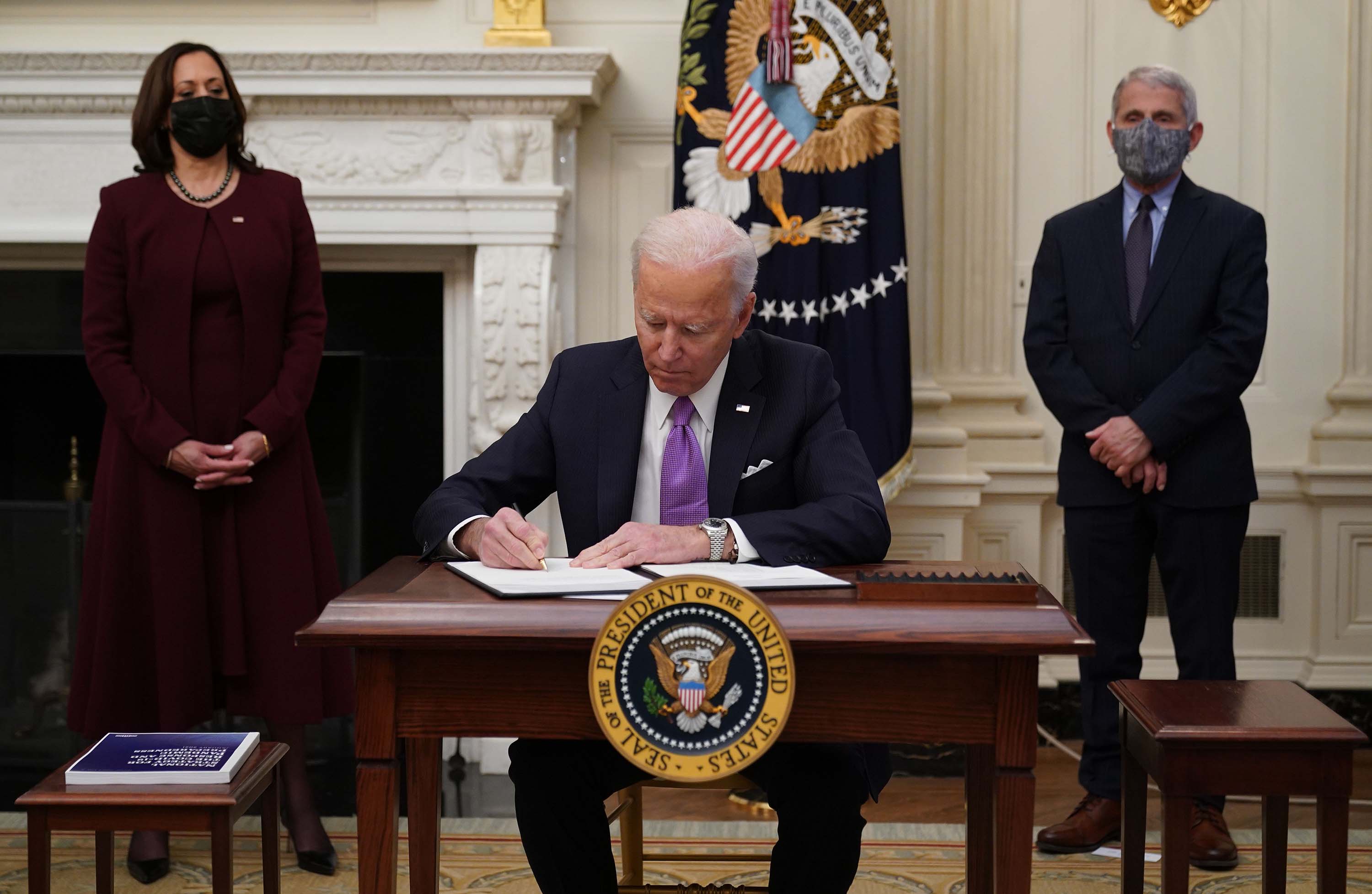 President Joe Biden signs executive orders as part of the Covid-19 response, as Vice President Kamala Harris, left, and Dr. Anthony Fauci look on, at the White House in Washington, DC, on January 21.