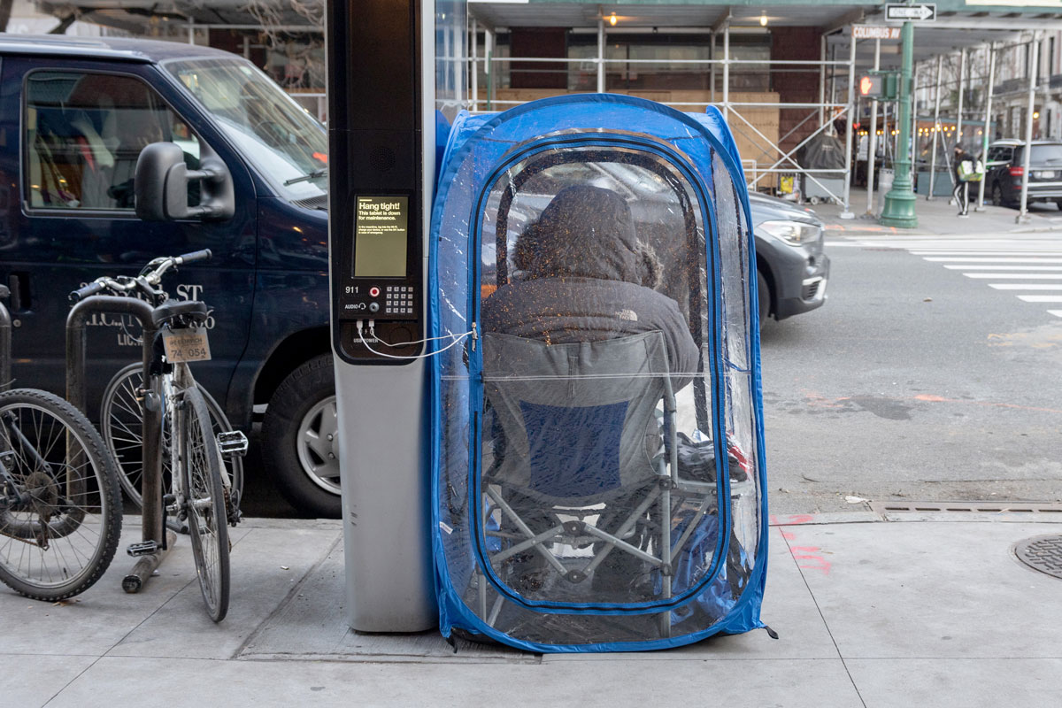 A person sits in a personal bubble while charging devices at a Link Wi-Fi station in New York City on December 29.