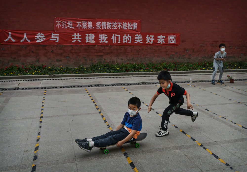 Boys play at a small park on May 6 in Beijing.The sign in the background reads in Chinese, "Don't get together, don't gather, pandemic control can't be relaxed. Everyone participates to collectively build our beautiful home." 