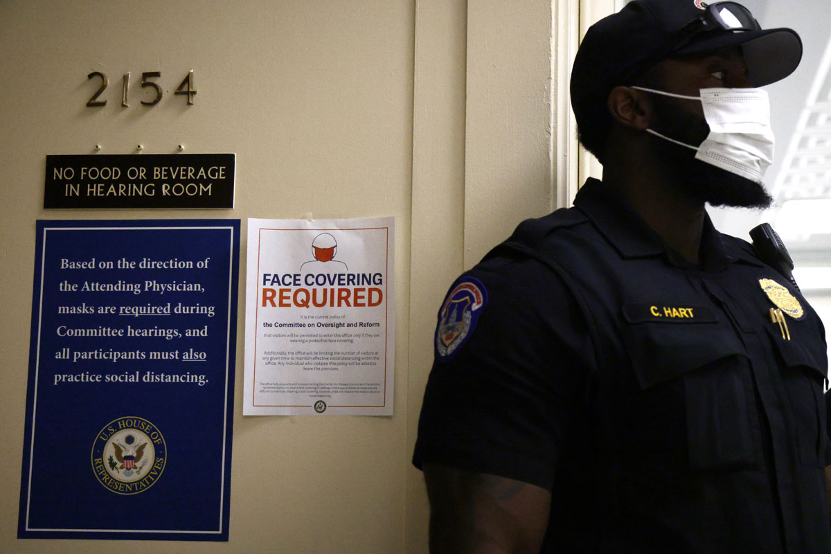 A Capitol Police officer wears a mask beside a sign about the new facial mask mandate posted outside a hearing room in Rayburn House Office Building on Washington, DC. on July 29.
