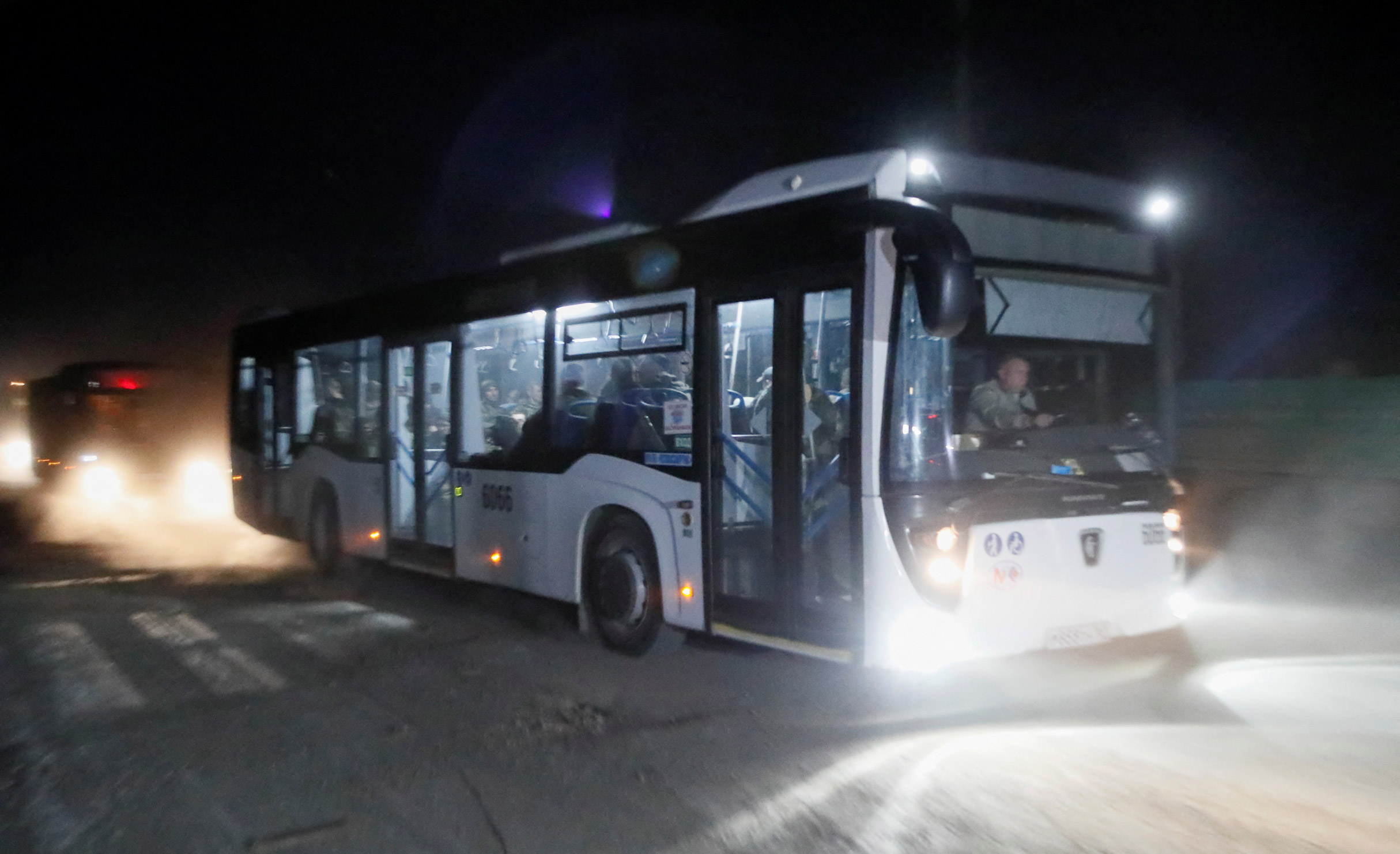 Buses carrying Ukrainian service members from the  Azovstal steel mill drive away under escort of the pro-Russian military in Mariupol, on Monday.