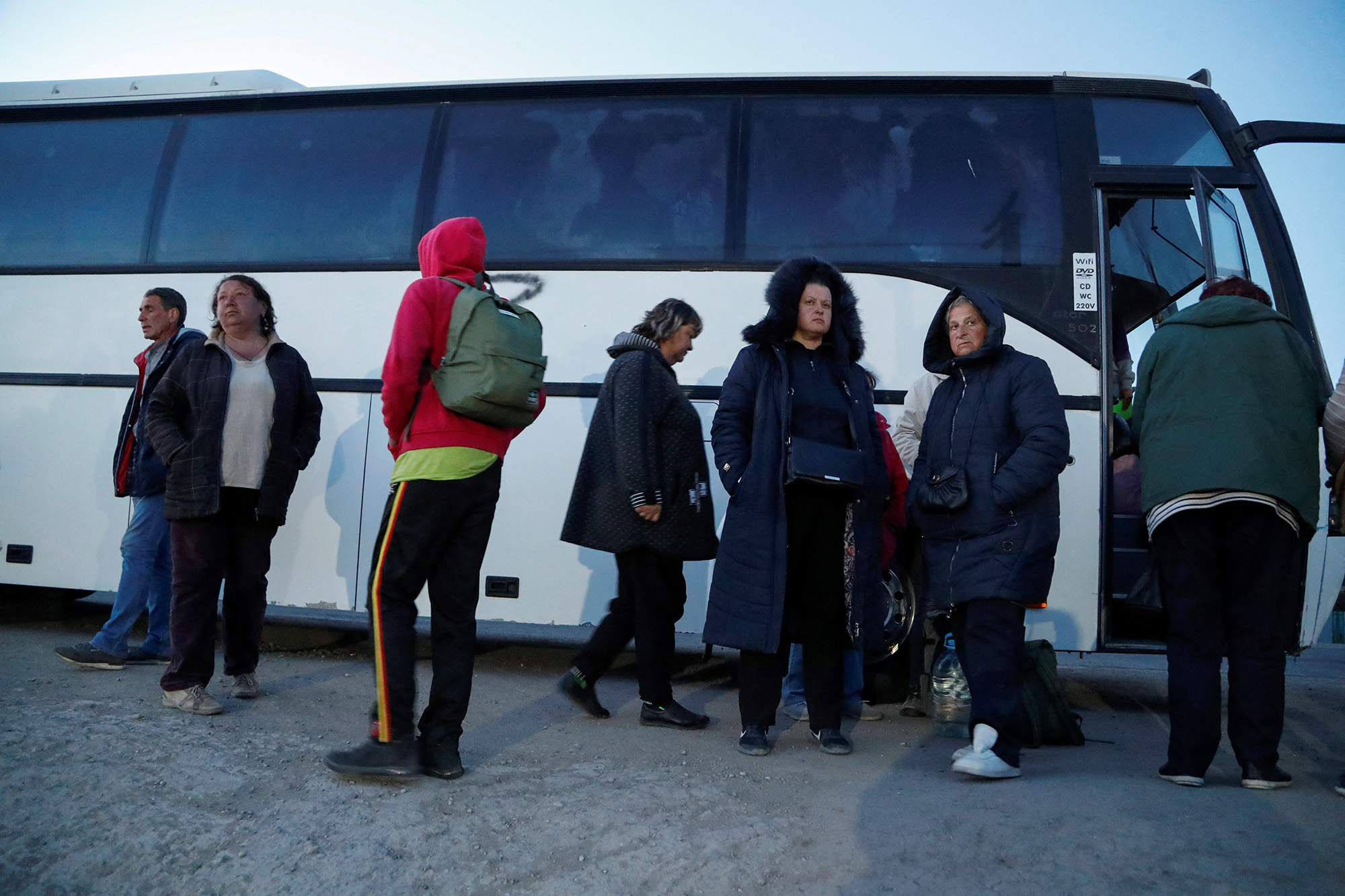 People evacuated from Mariupol stand near a bus at a temporary accommodation center in Bezimenne, Ukraine on May 7. 