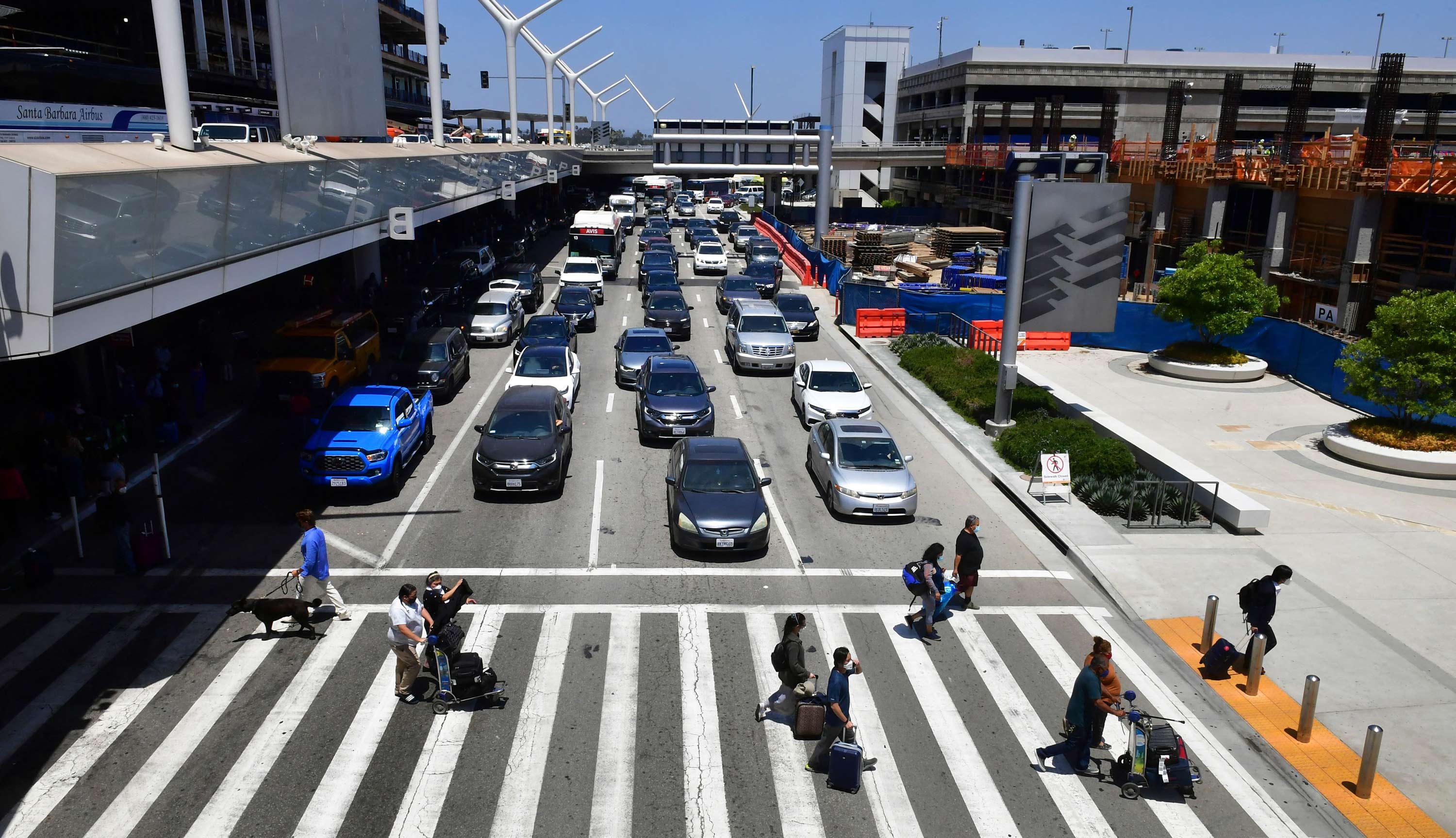 Travelers push their luggage on a crosswalk at Los Angeles International Airport on May 27 in Los Angeles.