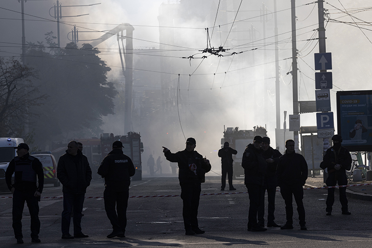 Members of the Ukrainian police force standing guard next to smoke as Ukraine's capital, Kyiv, was rocked by explosions during a drone attack in the early morning on October 17.