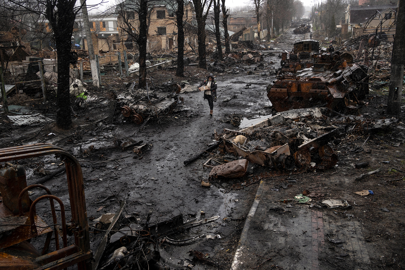 A woman walks amid destroyed Russian tanks in Bucha, in the outskirts of Kyiv, Ukraine, on Sunday, April 3. 
