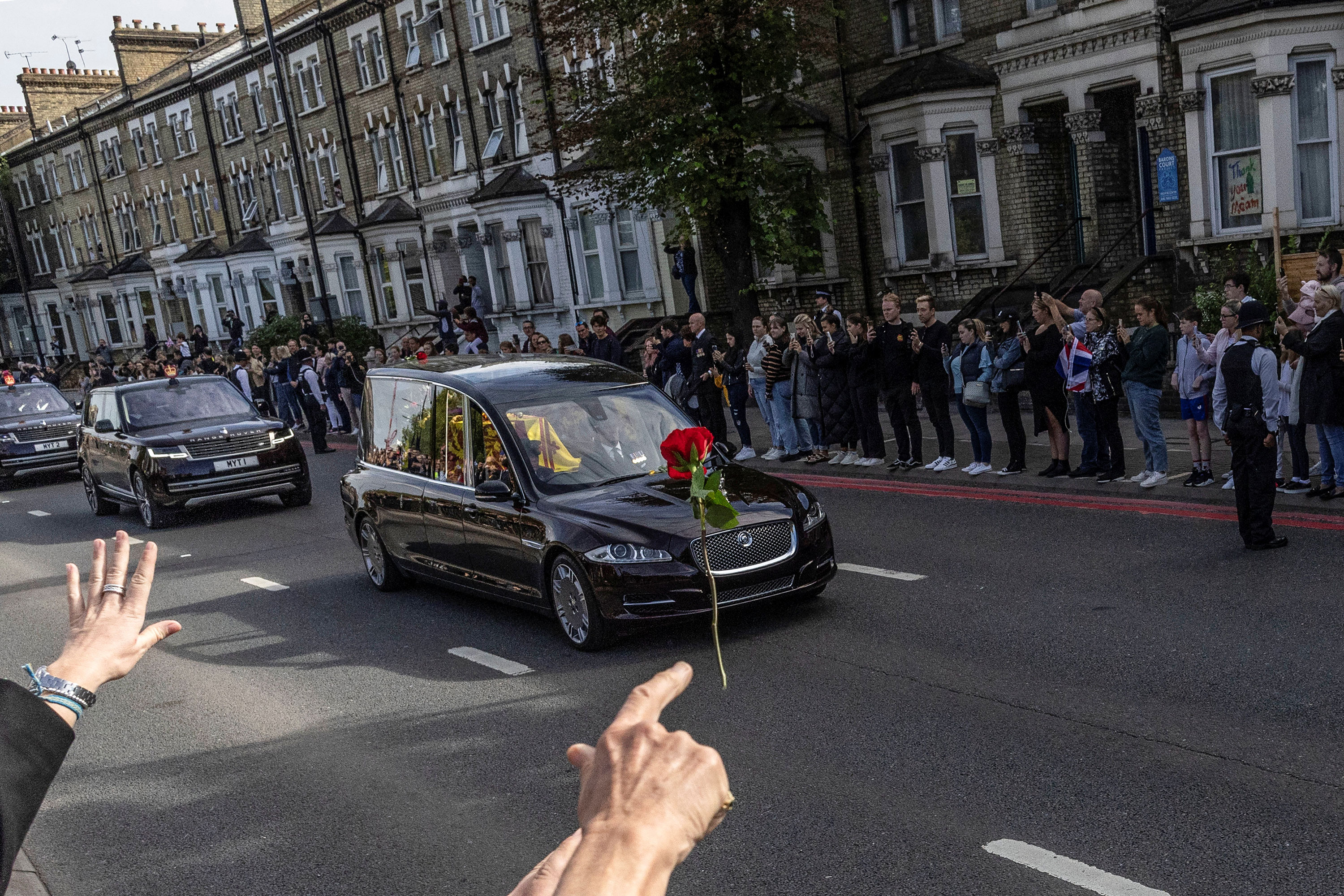A person throws a flower towards the Queen's hearse in west London.