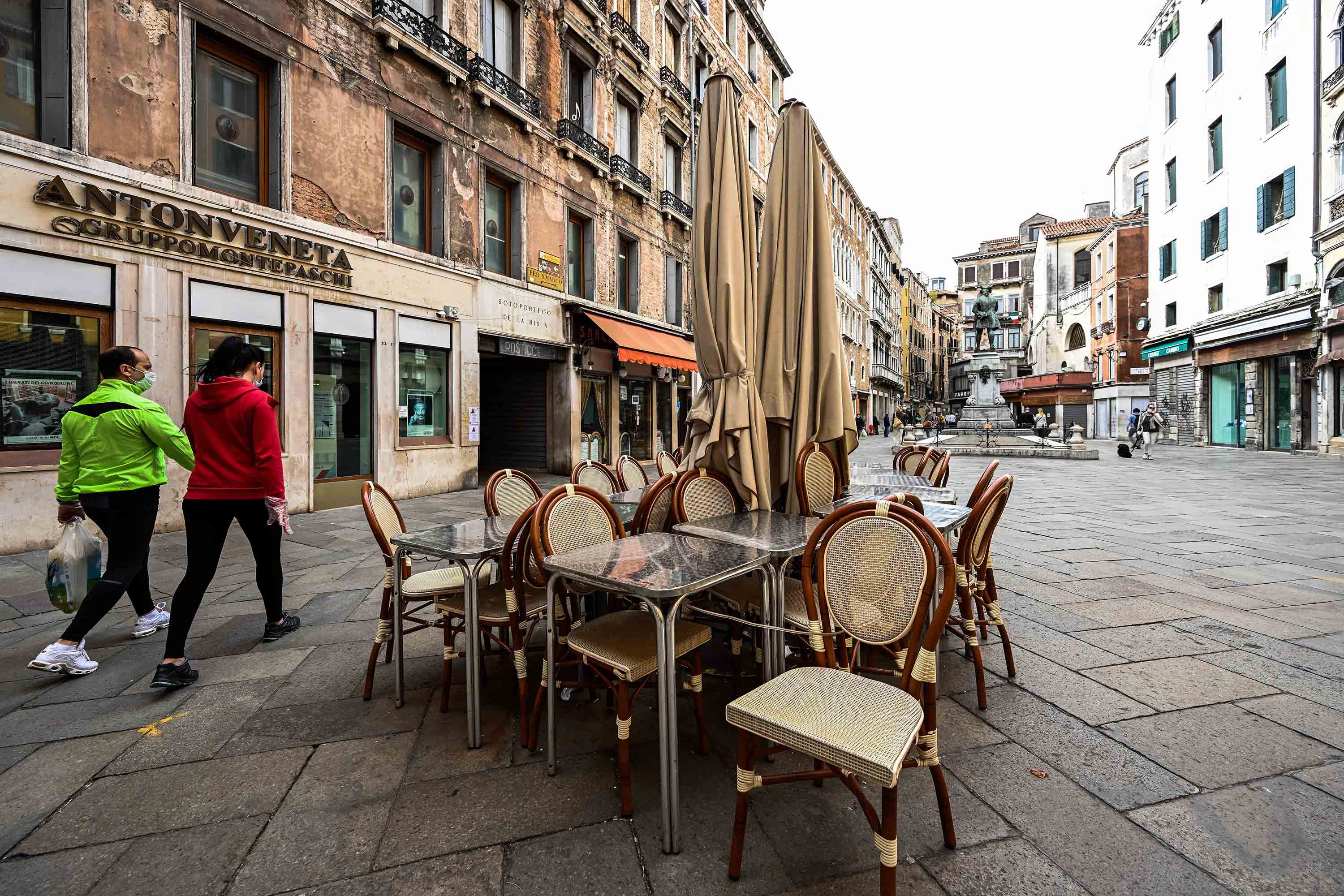 People walk past a closed cafe terrace in Venice, Italy, on May 13.