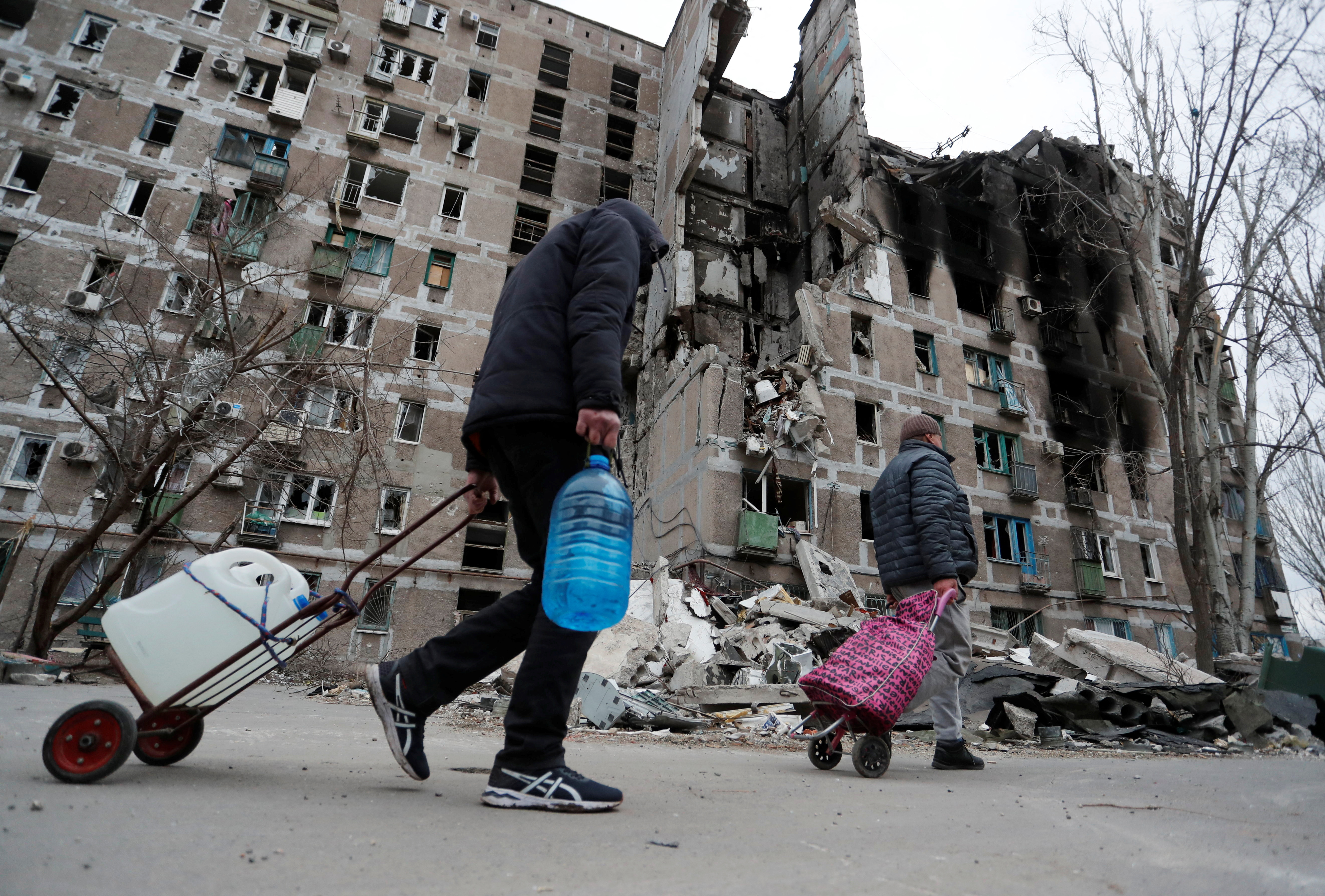 Local residents walk past an apartment building in the southern port city of Mariupol, Ukraine, on April 4.