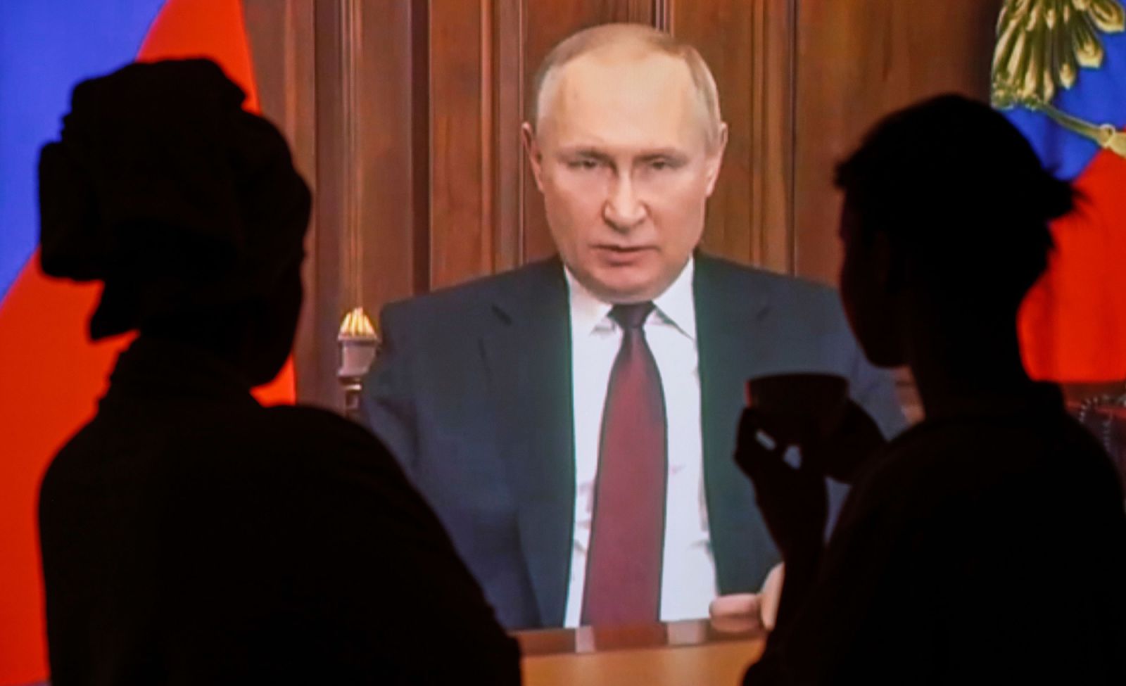 People in Moscow watch a televised address by Russian President Vladimir Putin as he announces a military operation in the Donbas region of eastern Ukraine on February 24.