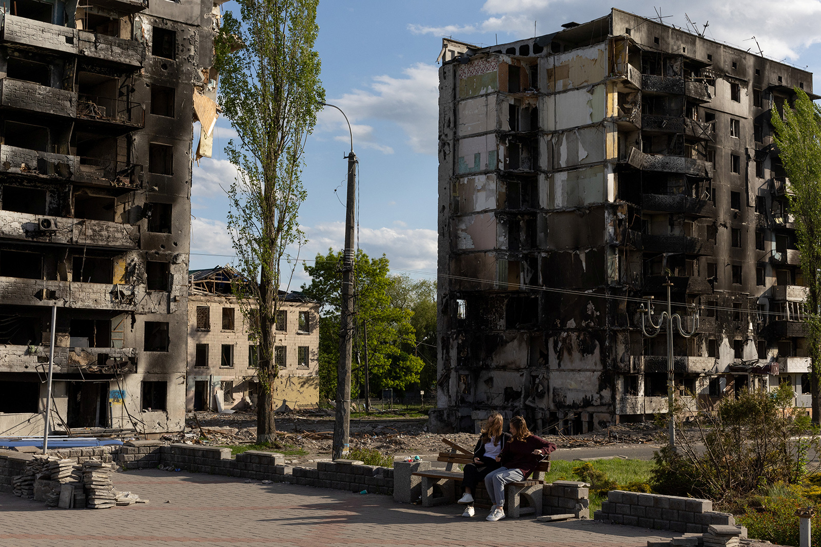 Two girls sit in a a public square in front of destroyed buildings in Borodyanka outside the Ukrainian capital of Kyiv, Ukraine on May 16.