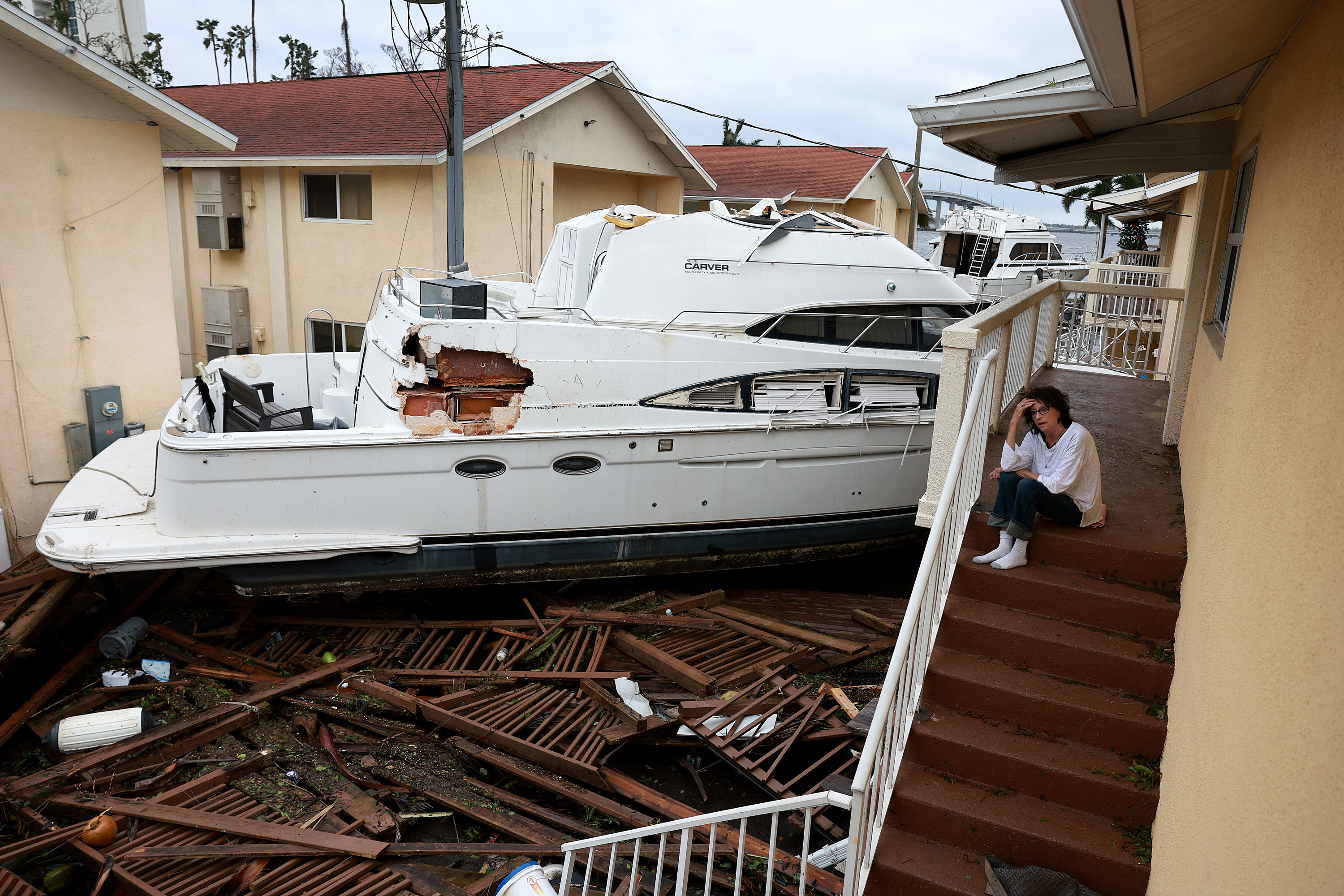 Brenda Brennan sits next to a boat that washed up against her apartment in Fort Myers, Florida, on Thursday.