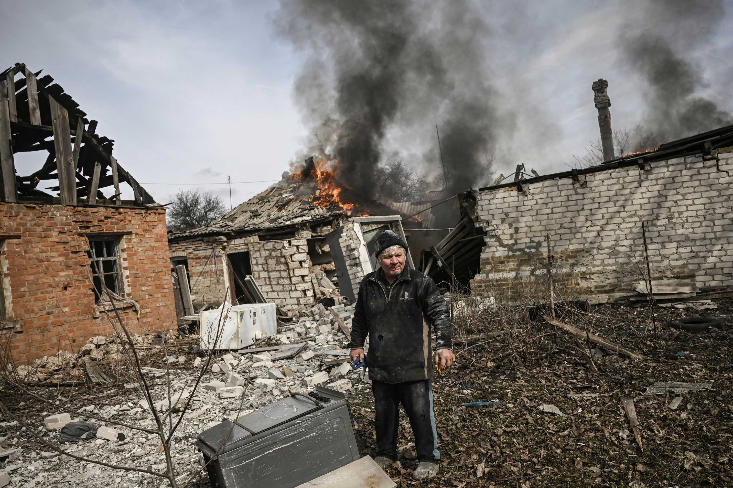 A man stands outside a burning house after shelling in the town of Chasiv Yar, near Bakhmut, on March 21. 