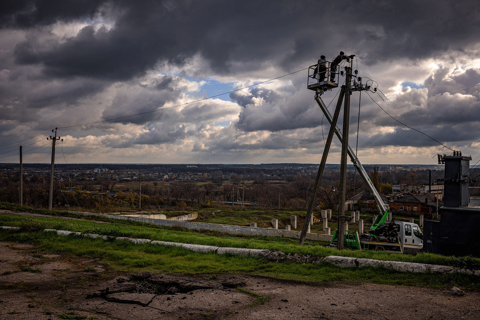 Communal workers repair power lines cut by shelling in the town of Kupiansk on November 3.