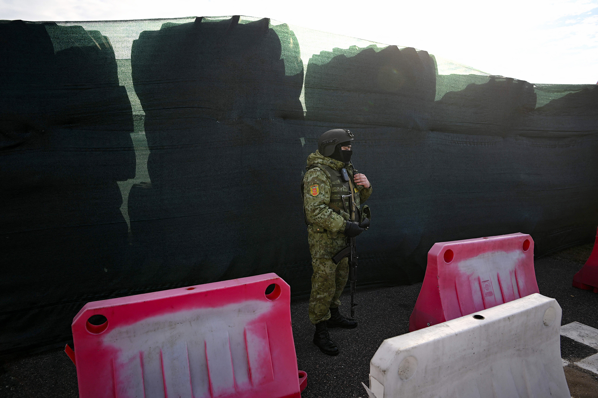 A Belarusian border guard keeps watch standing by a barricade made of truck tires at the Dyvin border crossing point between Belarus and Ukraine in the Brest region on February 15.