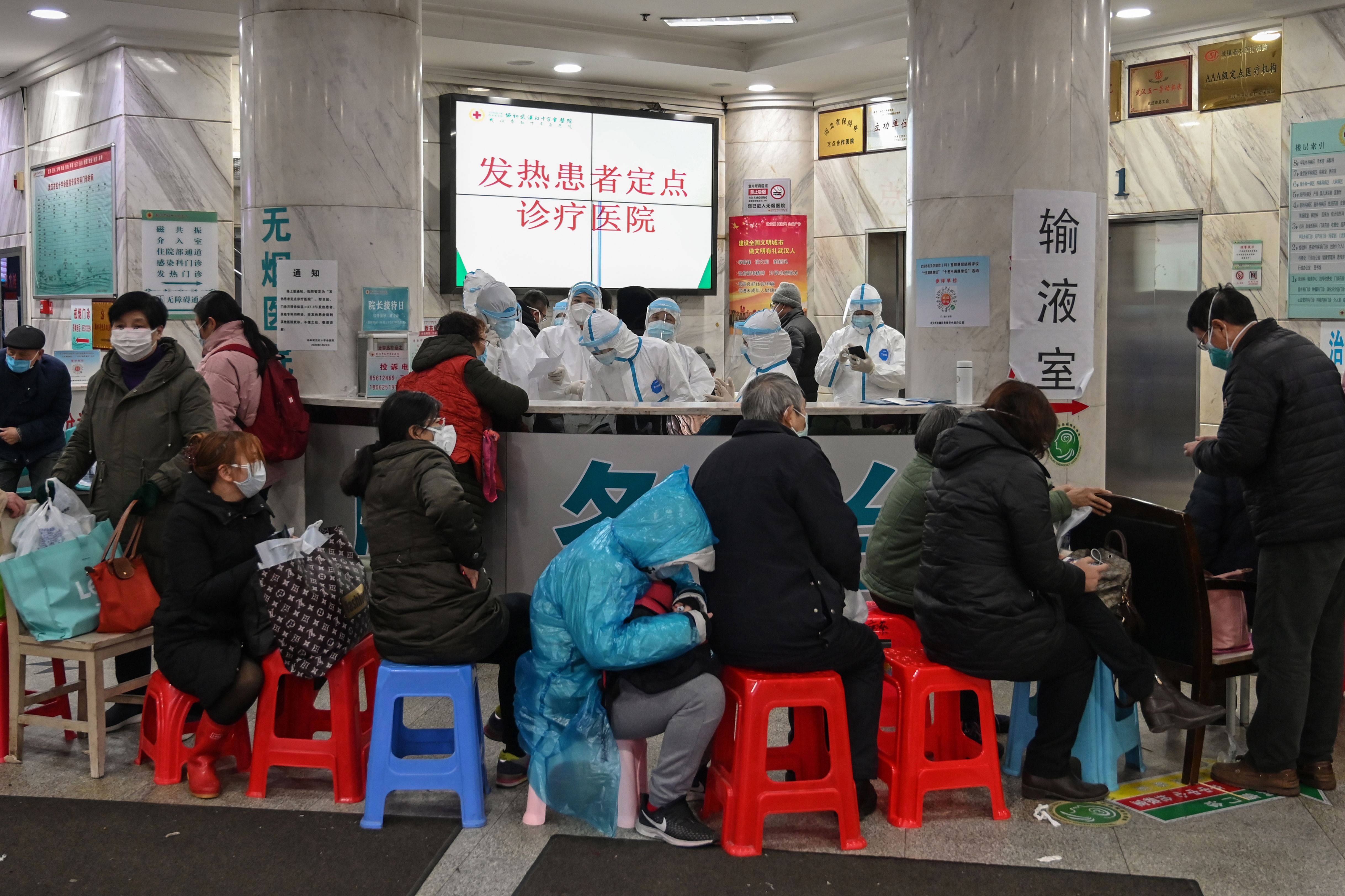 People wait as medical staff wear protective clothing to help stop the spread of the coronavirus at Wuhan Red Cross Hospital in Wuhan on January 25, 2020.