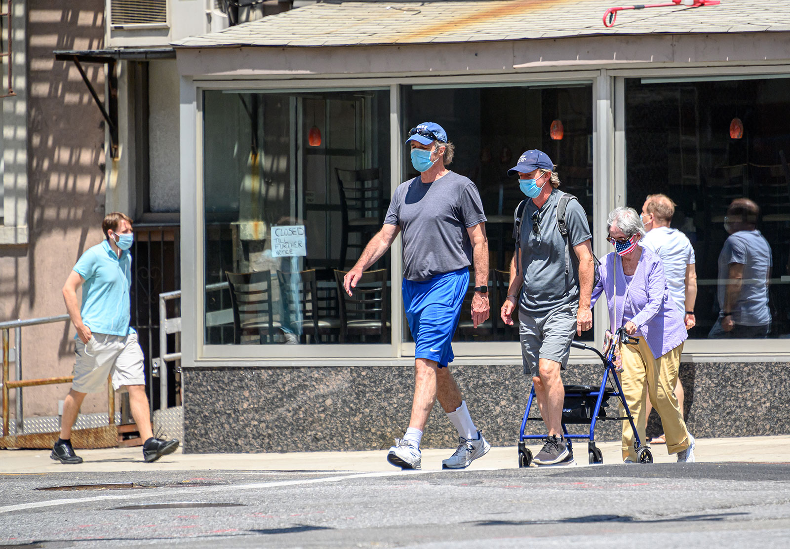 People wear face masks while walking in Manhattan on Tuesday, July 28. Dr. Anthony Fauci said on MSNBC Wednesday that universal wearing of masks is one of five principles that could help stop coronavirus surges happening in states. 