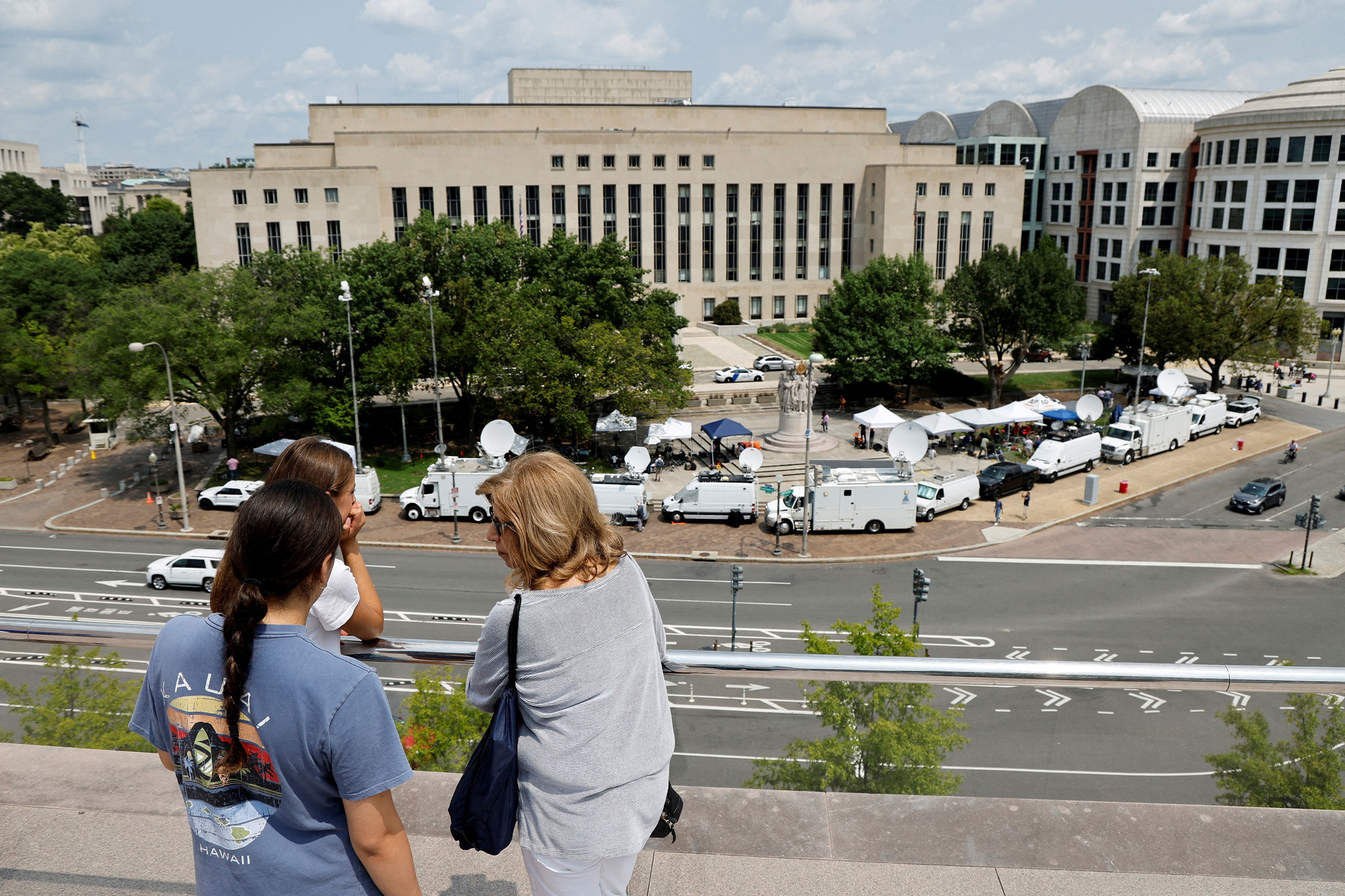 Tourists atop the National Gallery of Art look out over the news trucks in front of the federal courthouse on Wednesday where former President Donald Trump will appear.