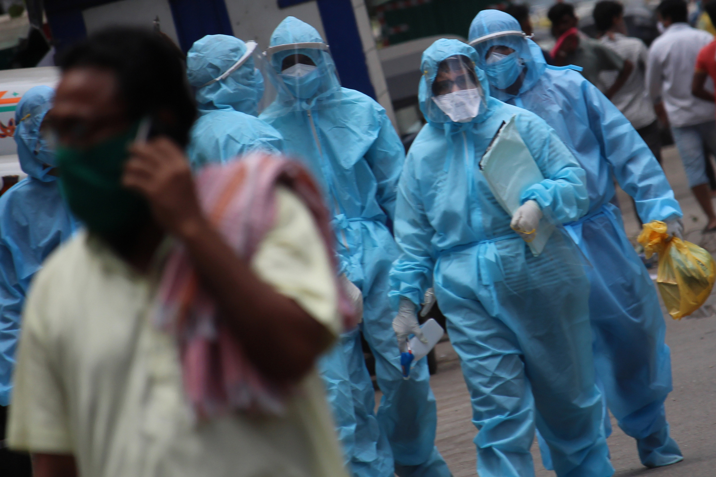 Healthcare workers wearing protective suits walk along a street in the Dharavi slum area of Mumbai, India on Sunday, June 7. 