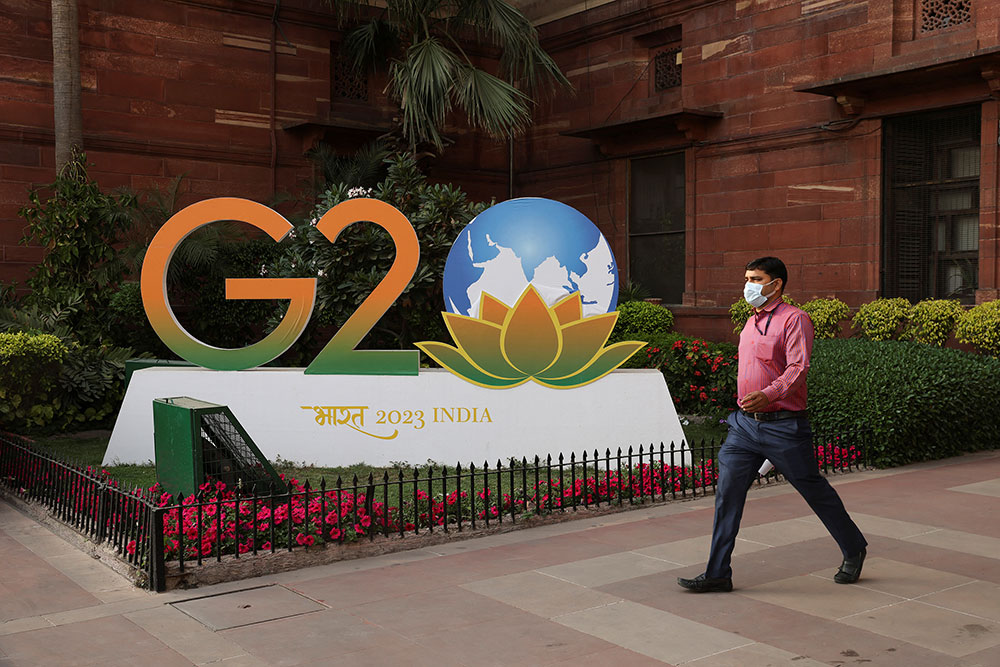 Seorang pria berjalan melewati model logo G20 di luar kementerian keuangan di New Delhi, India, pada 1 Maret. 