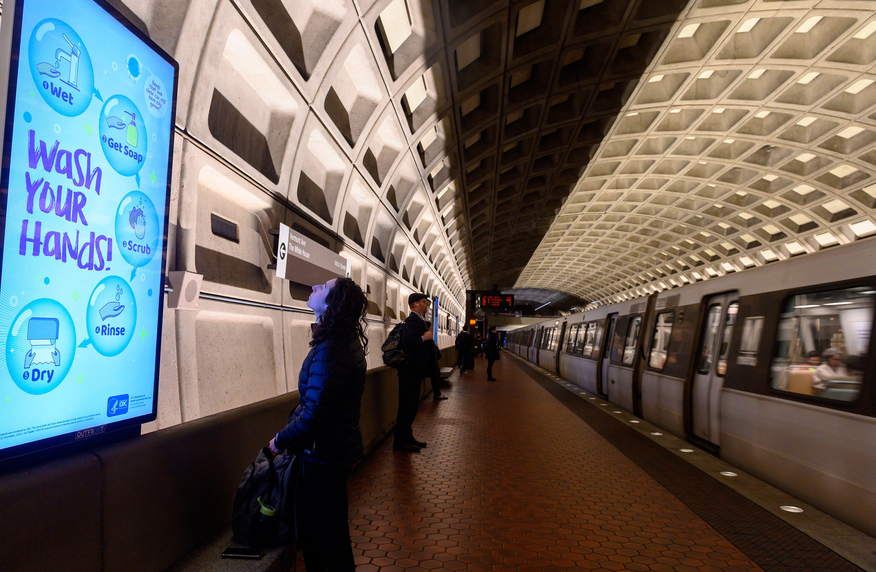 A woman reads a public awareness sign in response to the coronavirus outbreak as she waits for a train in the DC Metro on March 10. 