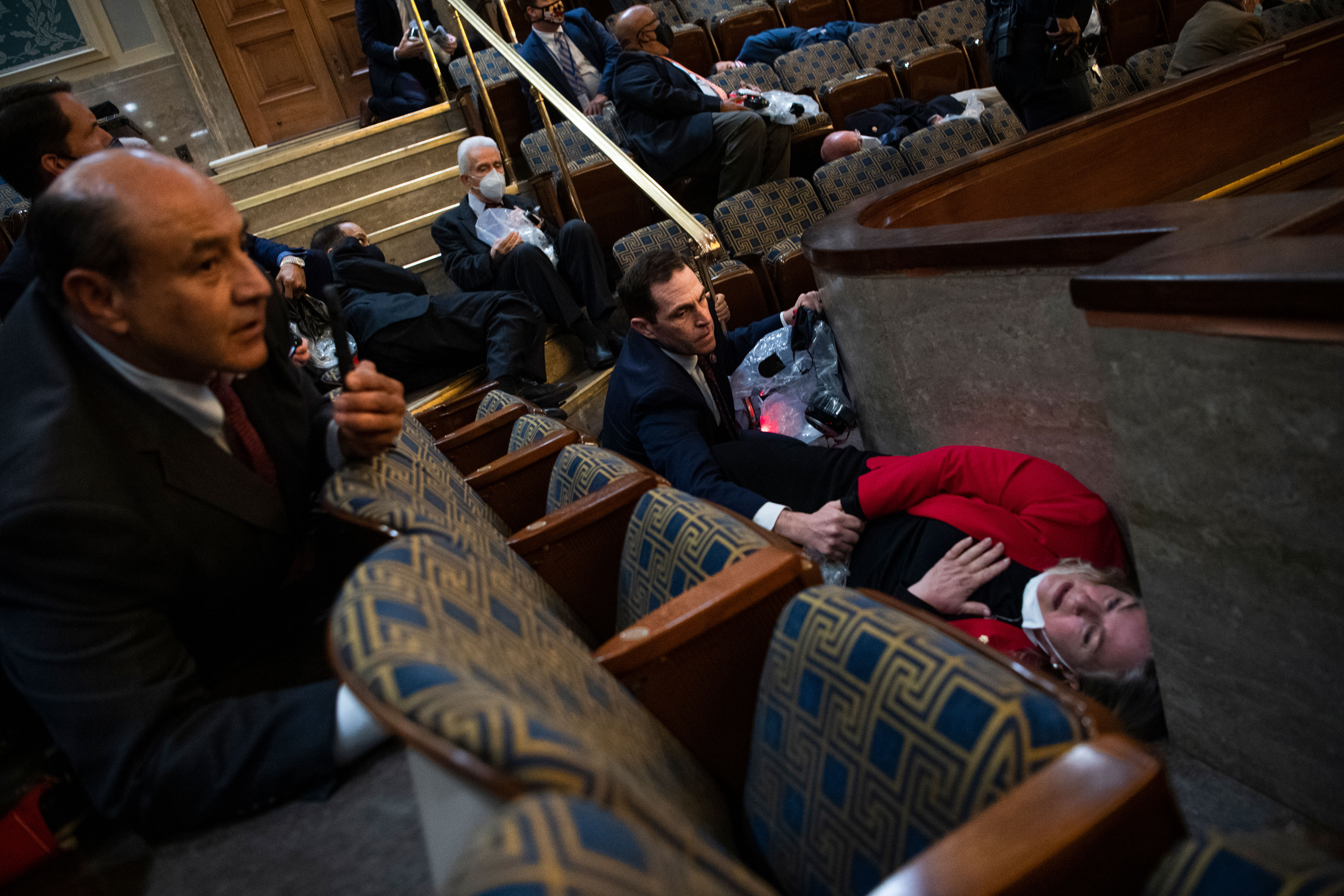 Rep. Jason Crow comforts Rep. Susan Wild, on the floor in red, while taking cover as pro-Trump rioters breach the Capitol on January 6.