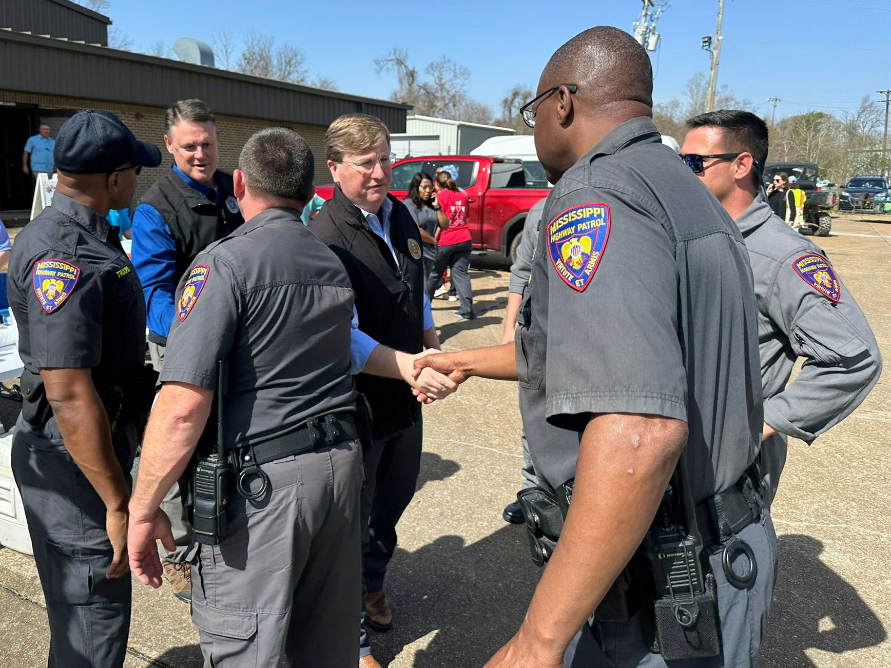 Mississippi Gov. Tate Reeves shakes hands with a highway patrol officer as he visits volunteers helping in the aftermath of a tornado in Rolling Fork, Mississippi, on March 25.