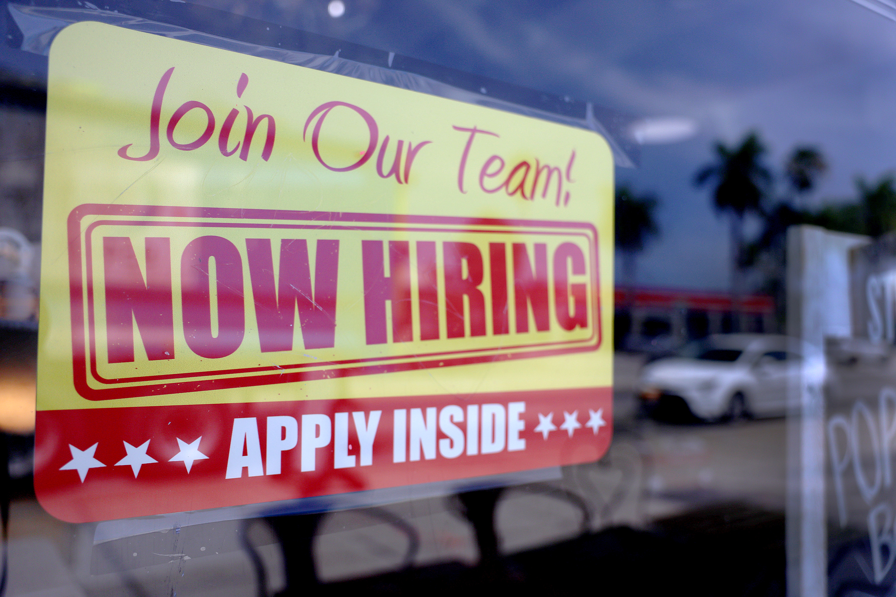 A 'Now Hiring' sign posted in the window of a restaurant looking to hire workers on May 5, 2023 in Miami, Florida. 