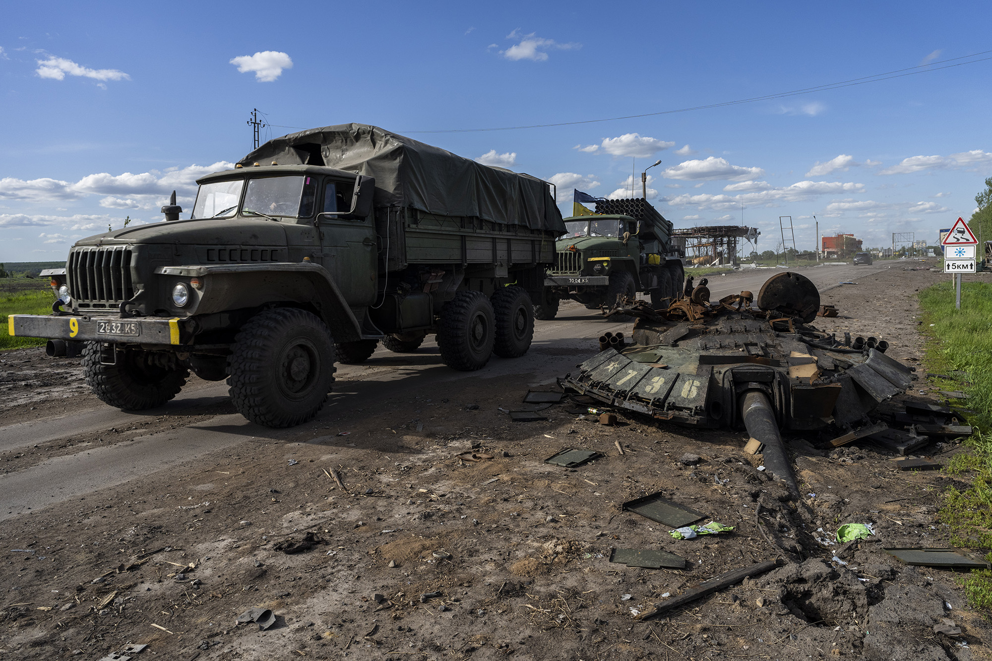 Ukrainian Army vehicles drive past the remains of a Russian tank near Kharkiv on Friday, May 13.