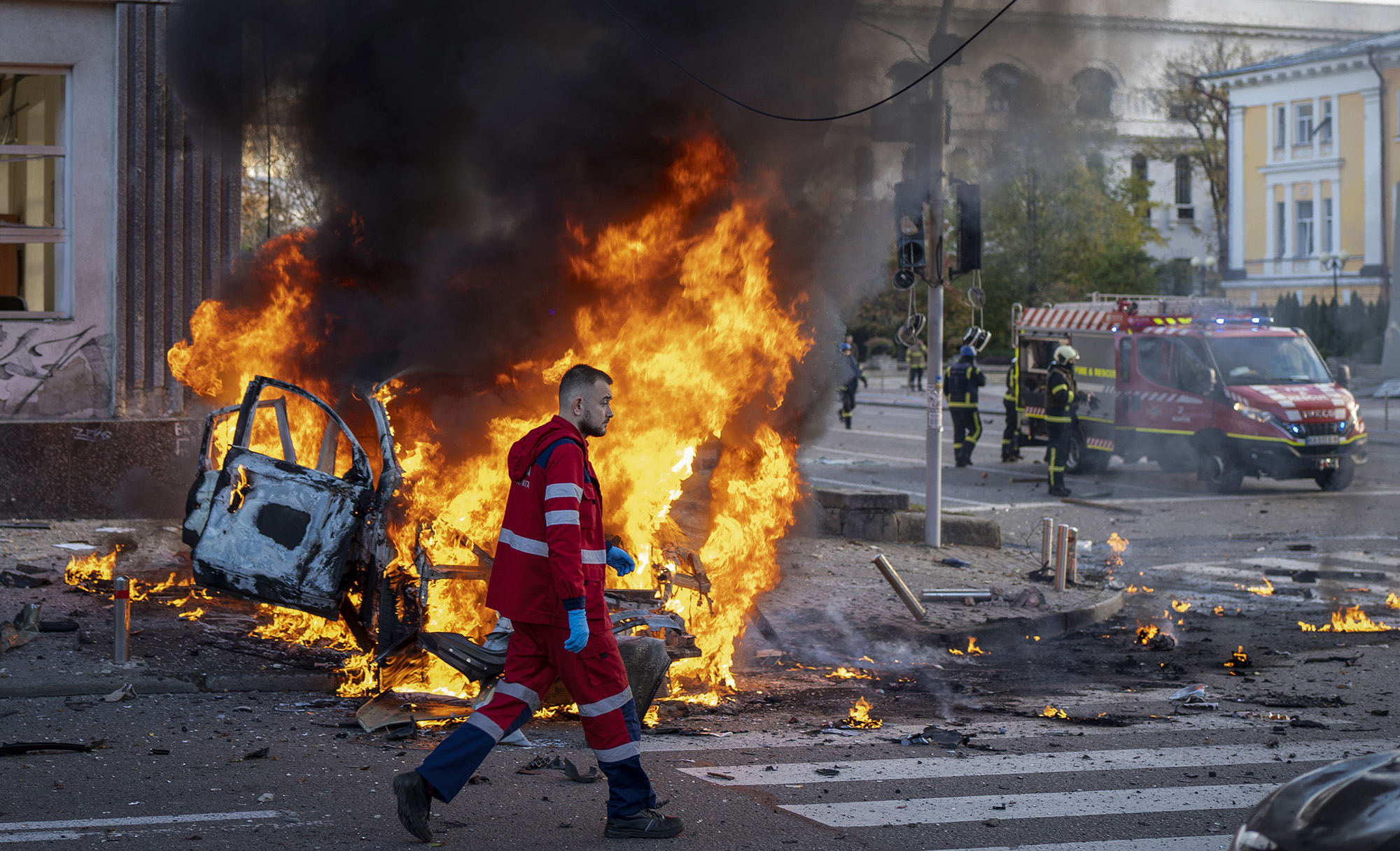 A medical worker runs past a burning car after a Russian attack in Kyiv, Ukraine on October 10.