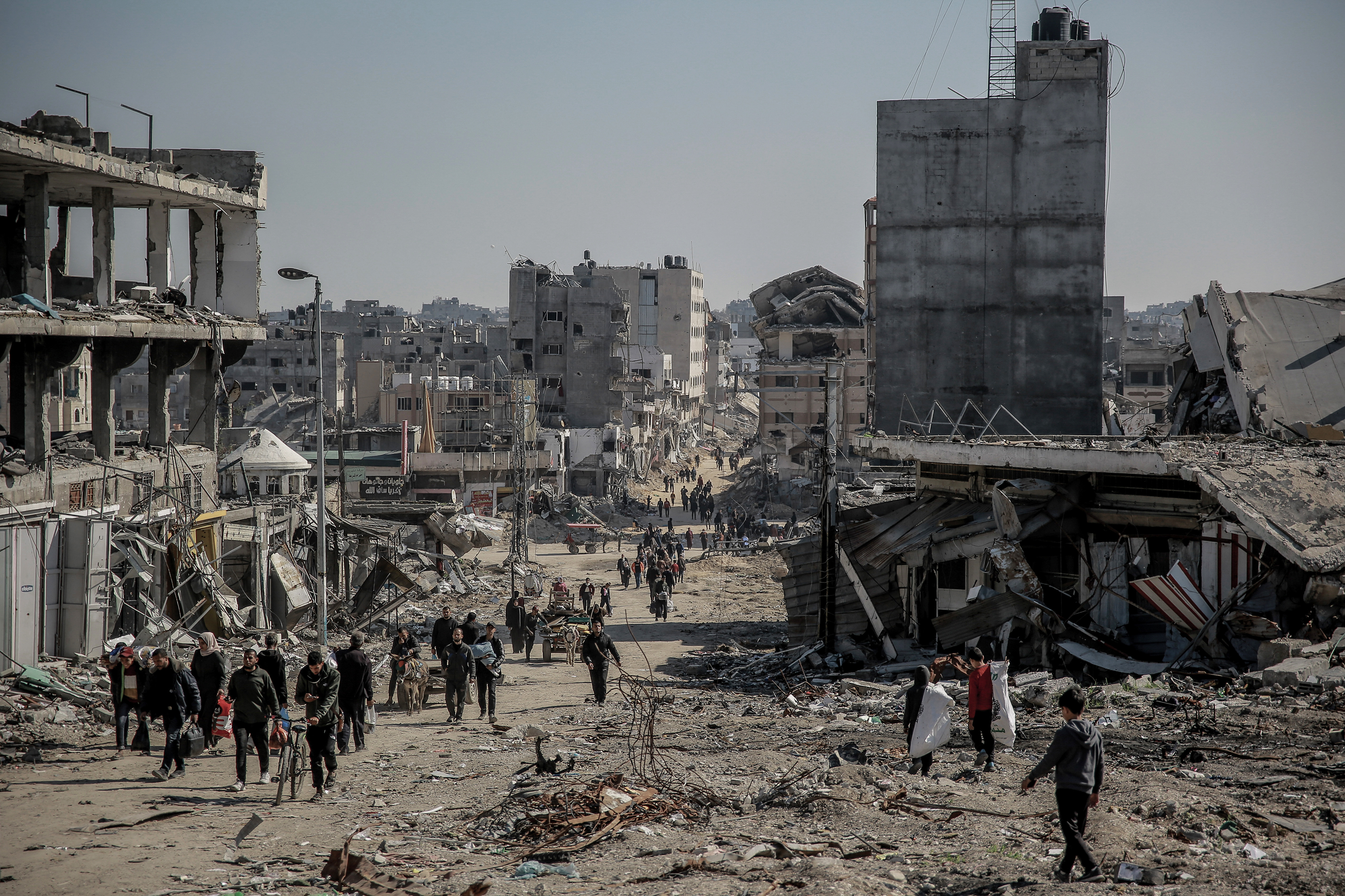 Palestinians walk next to damaged buildings in Gaza City, on February 11.
