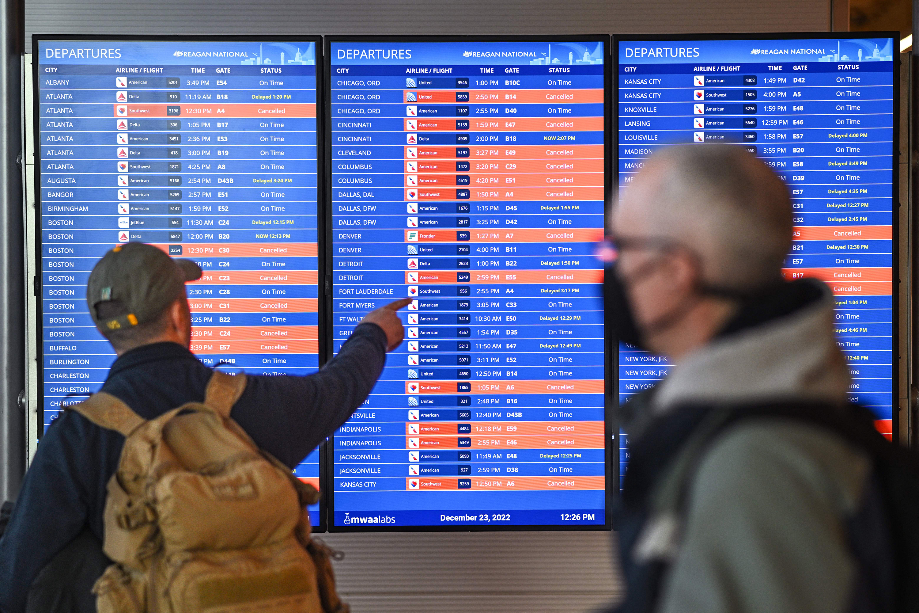 Passengers look at information boards showing flight cancellations and delays at Reagan National Airport in Arlington, Virginia, on Dec. 23.