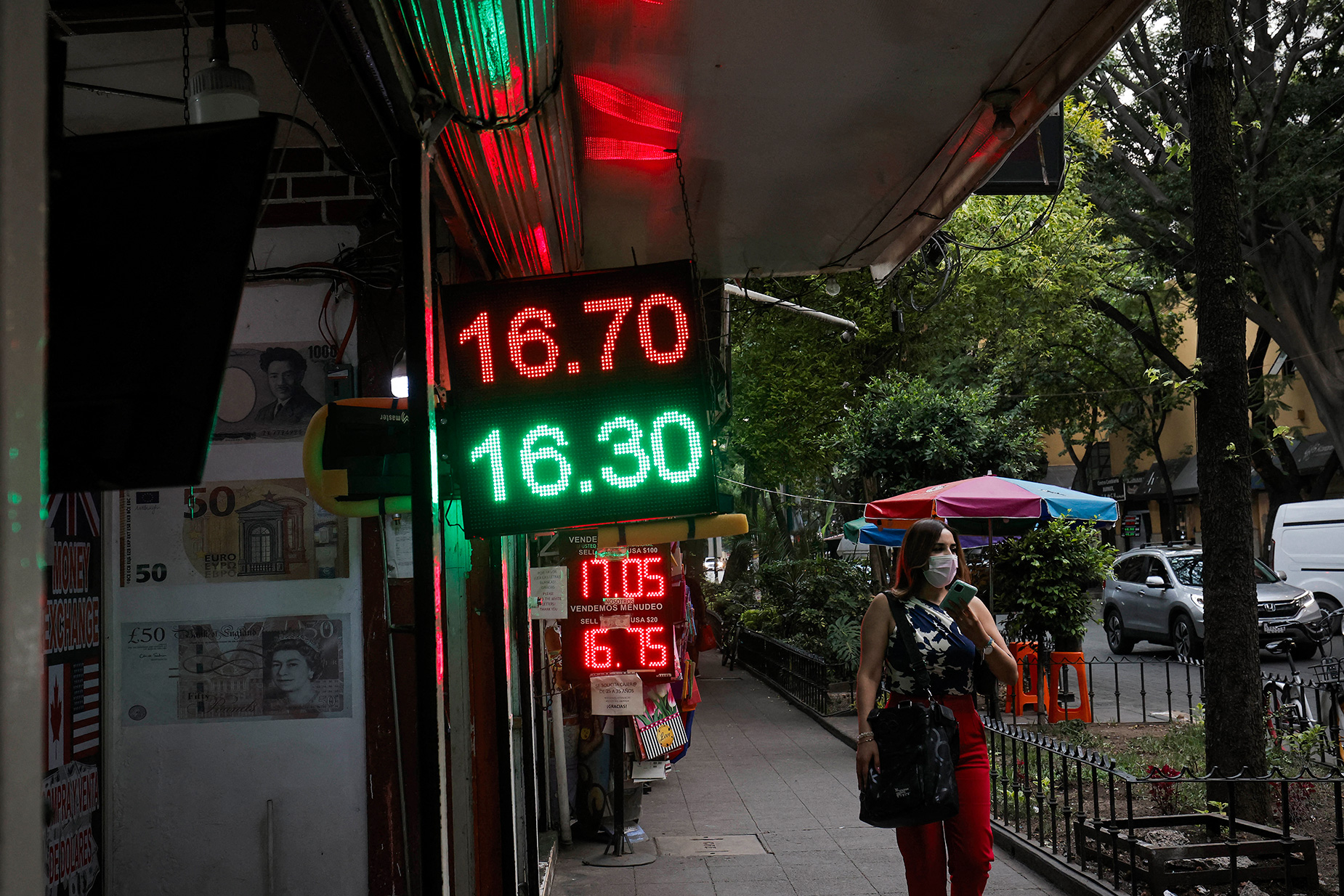 A woman walks past a board showing currency exchange rates of the Mexican peso against the US dollar in Mexico City, on May 28. 