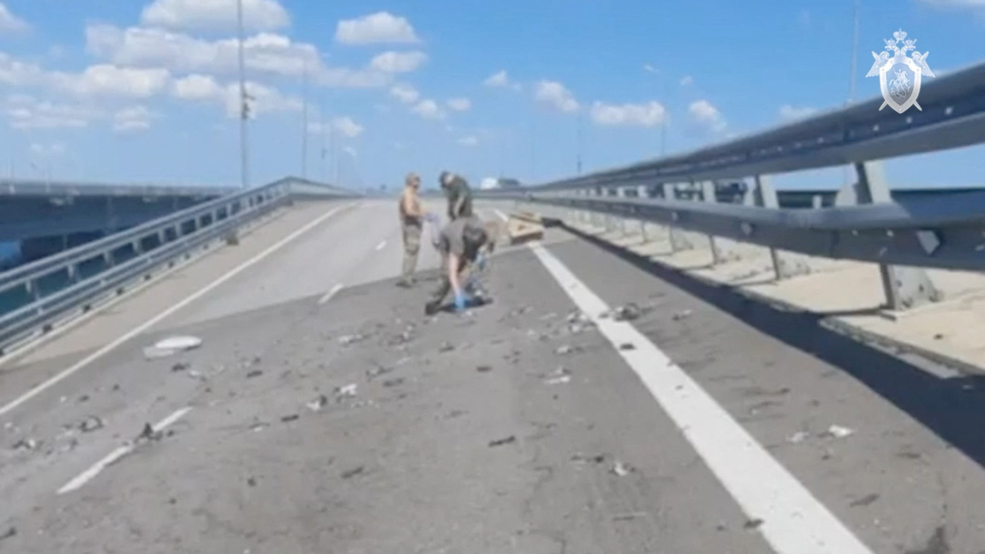 Russian investigators work at the scene on the section of a road sloping to one side following an alleged attack on the Crimea Bridge across the Kerch Strait, in this still image taken from video released on July 17.
